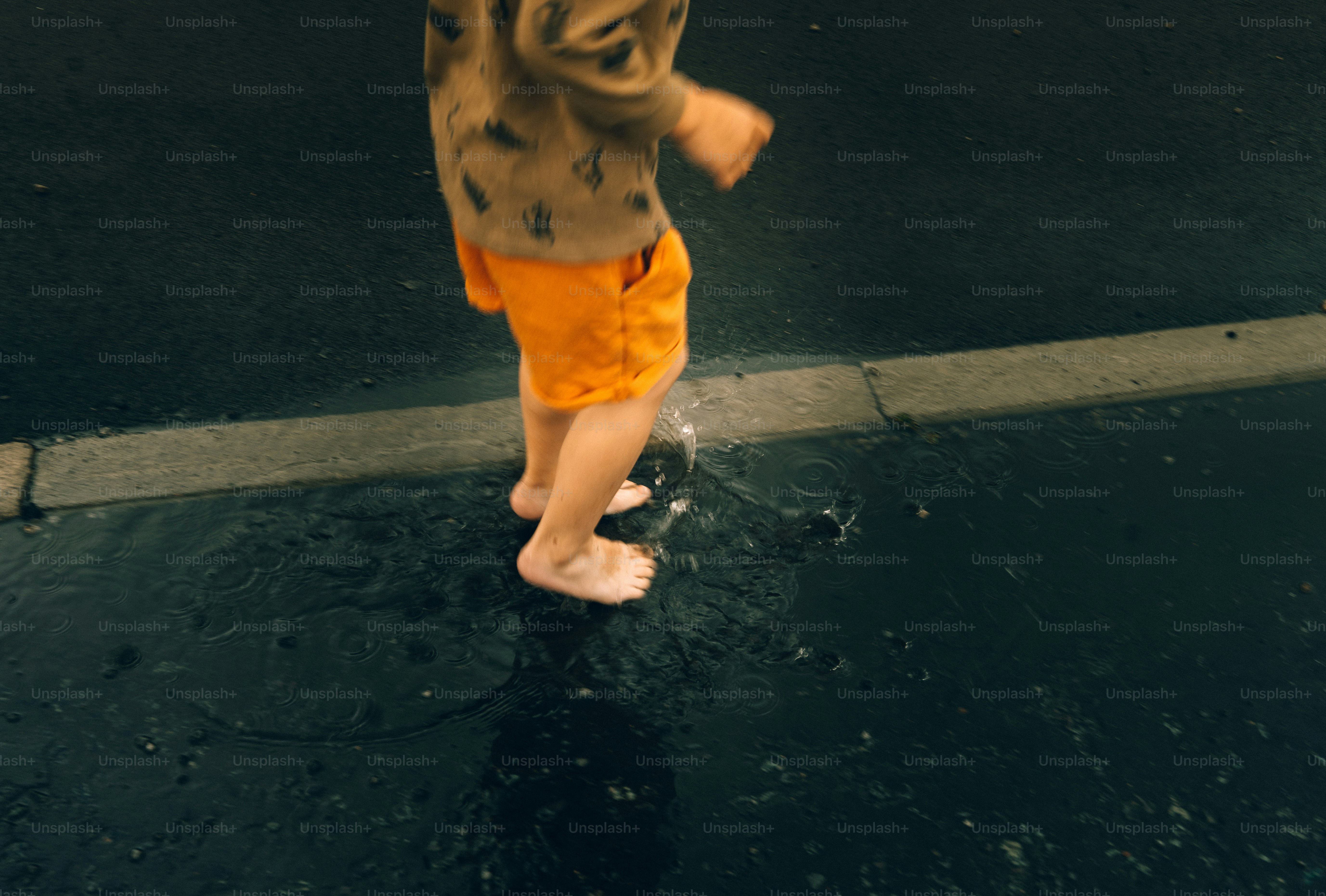 Child splashing in puddles on a wet street