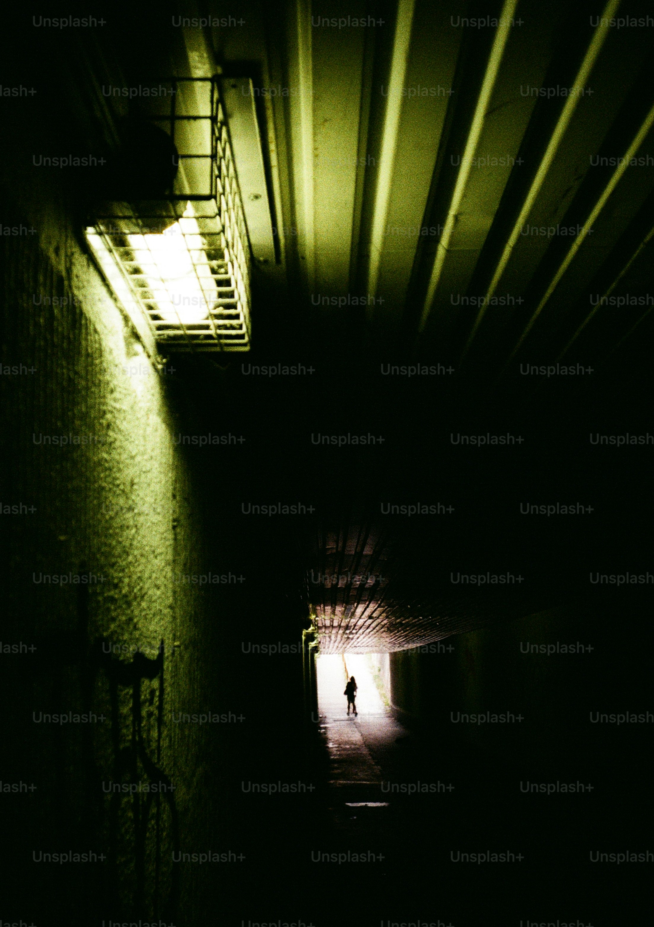 Silhouette of person walking in dark tunnel
