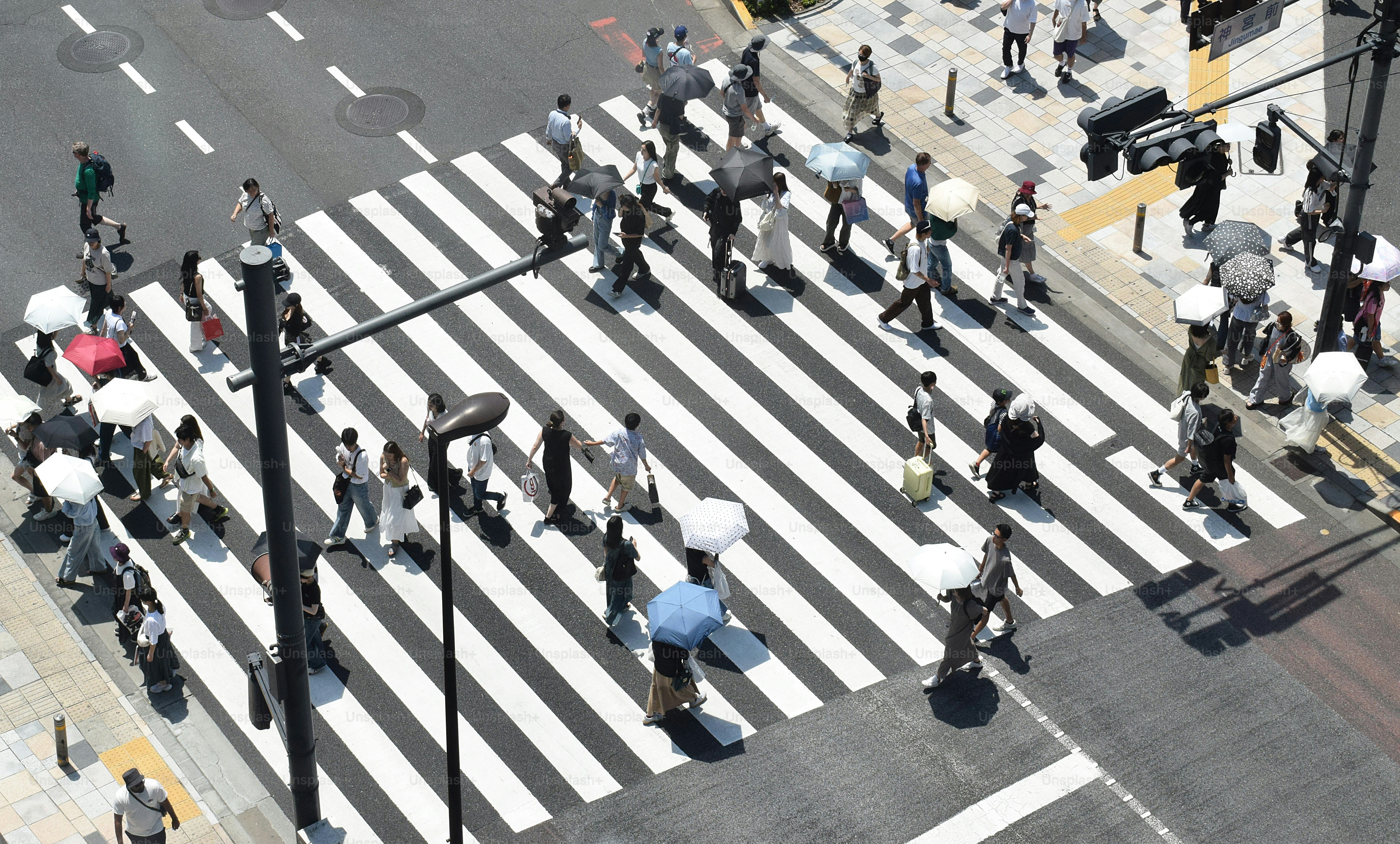 People crossing a busy street on a sunny day.