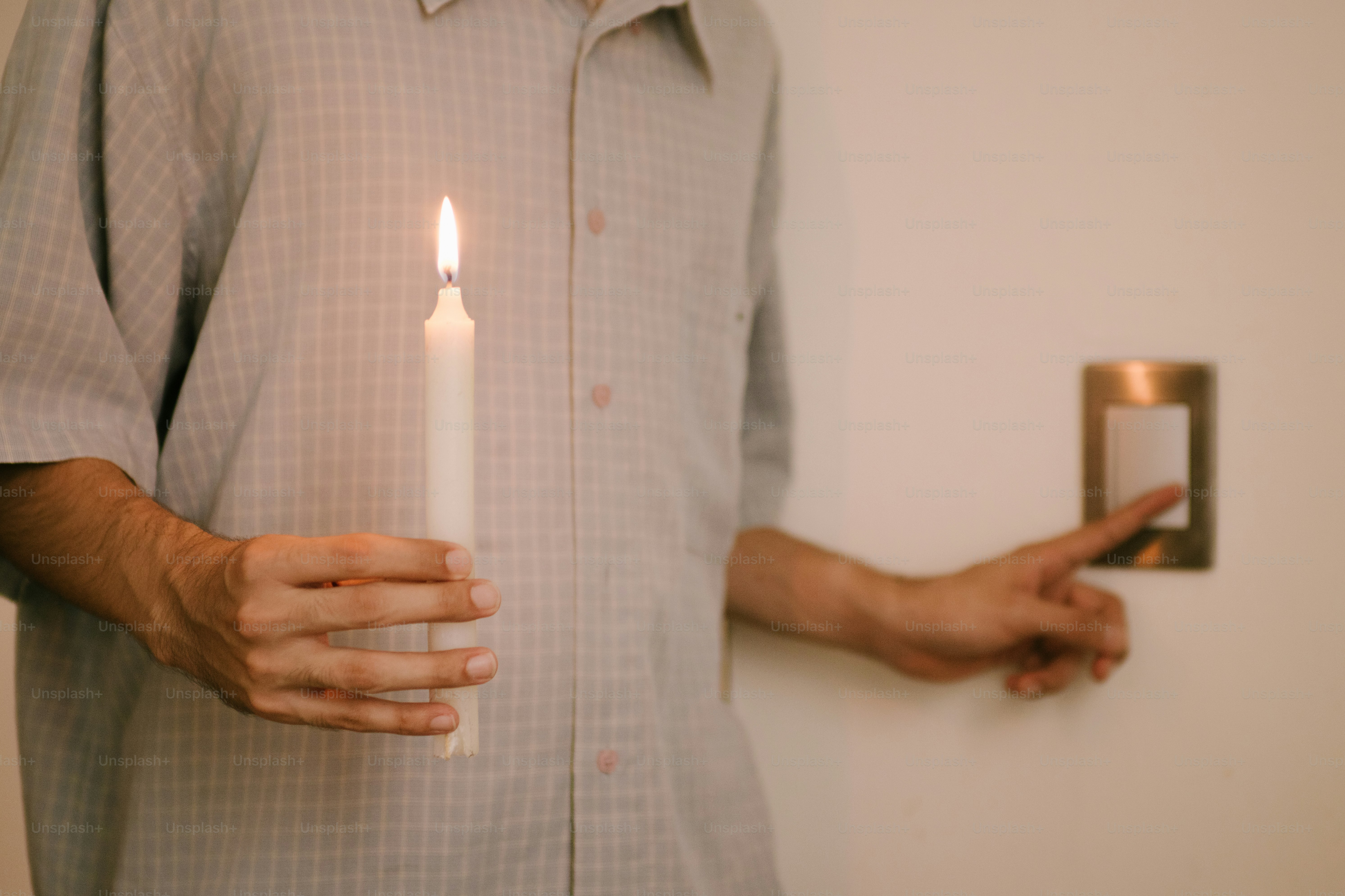 Person holding a lit candle near a doorbell