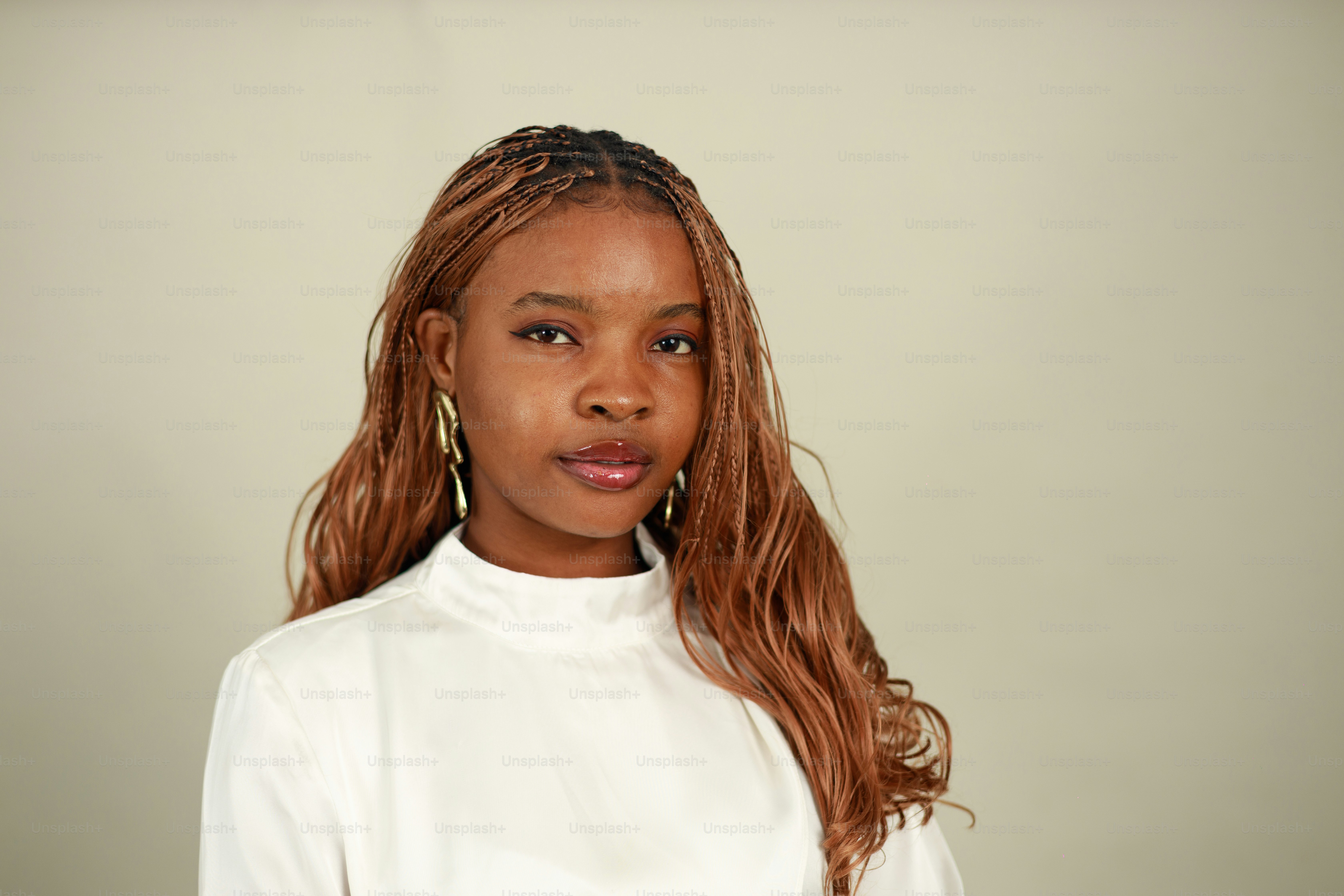 Young woman with braided hair and hoop earrings.