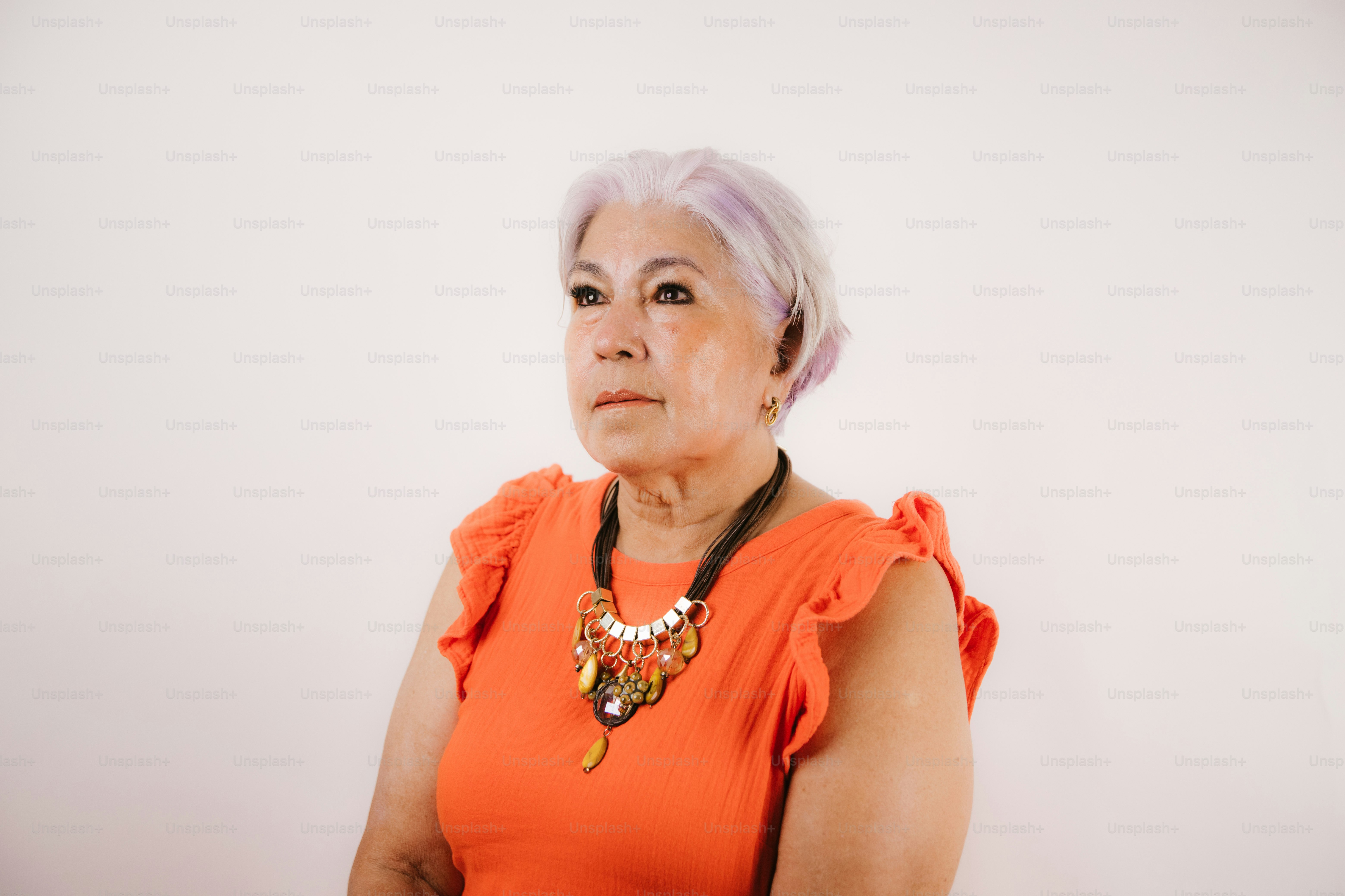 Elderly woman with purple hair wearing orange dress