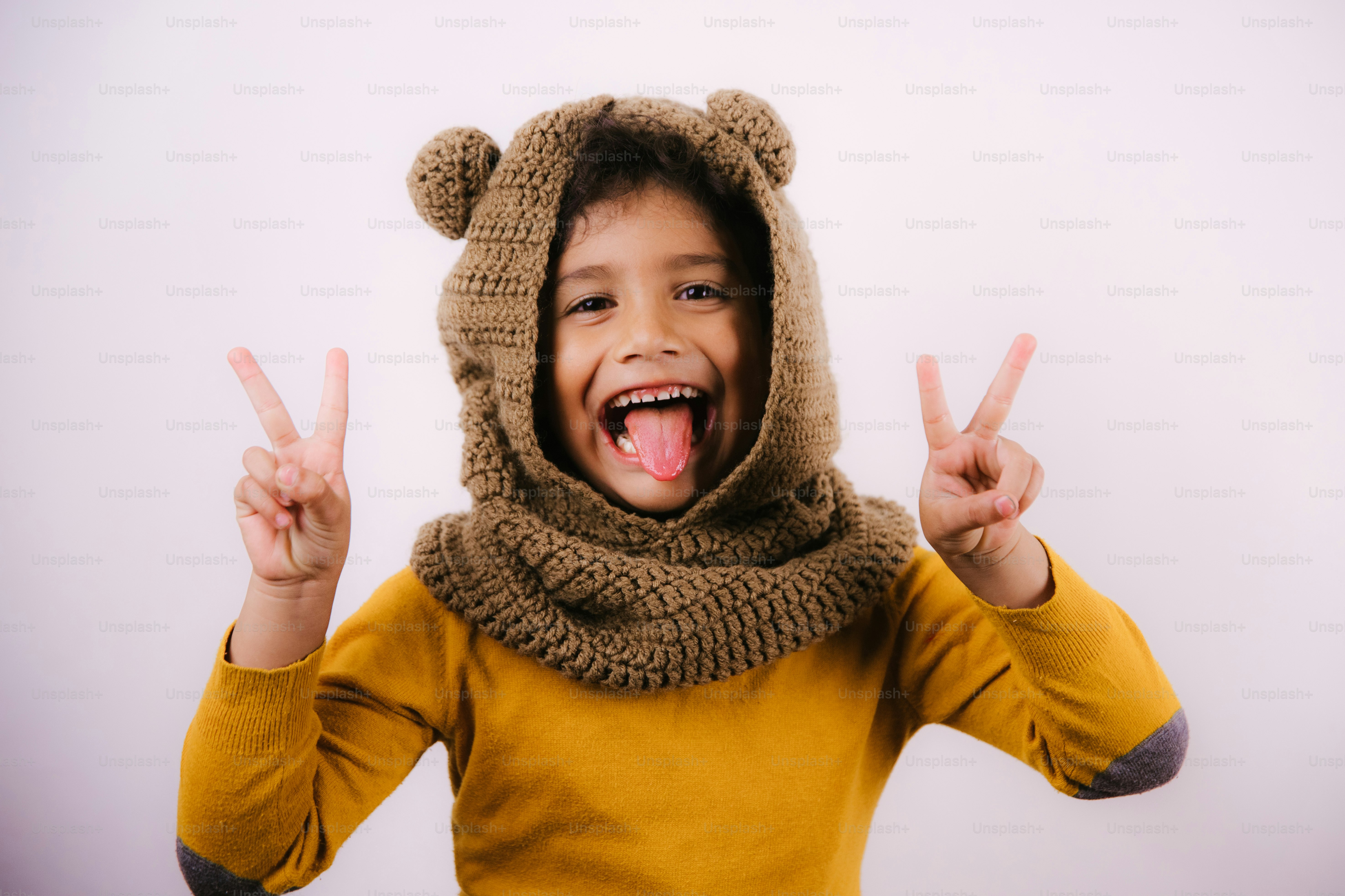 Child wearing a bear hood makes peace signs.
