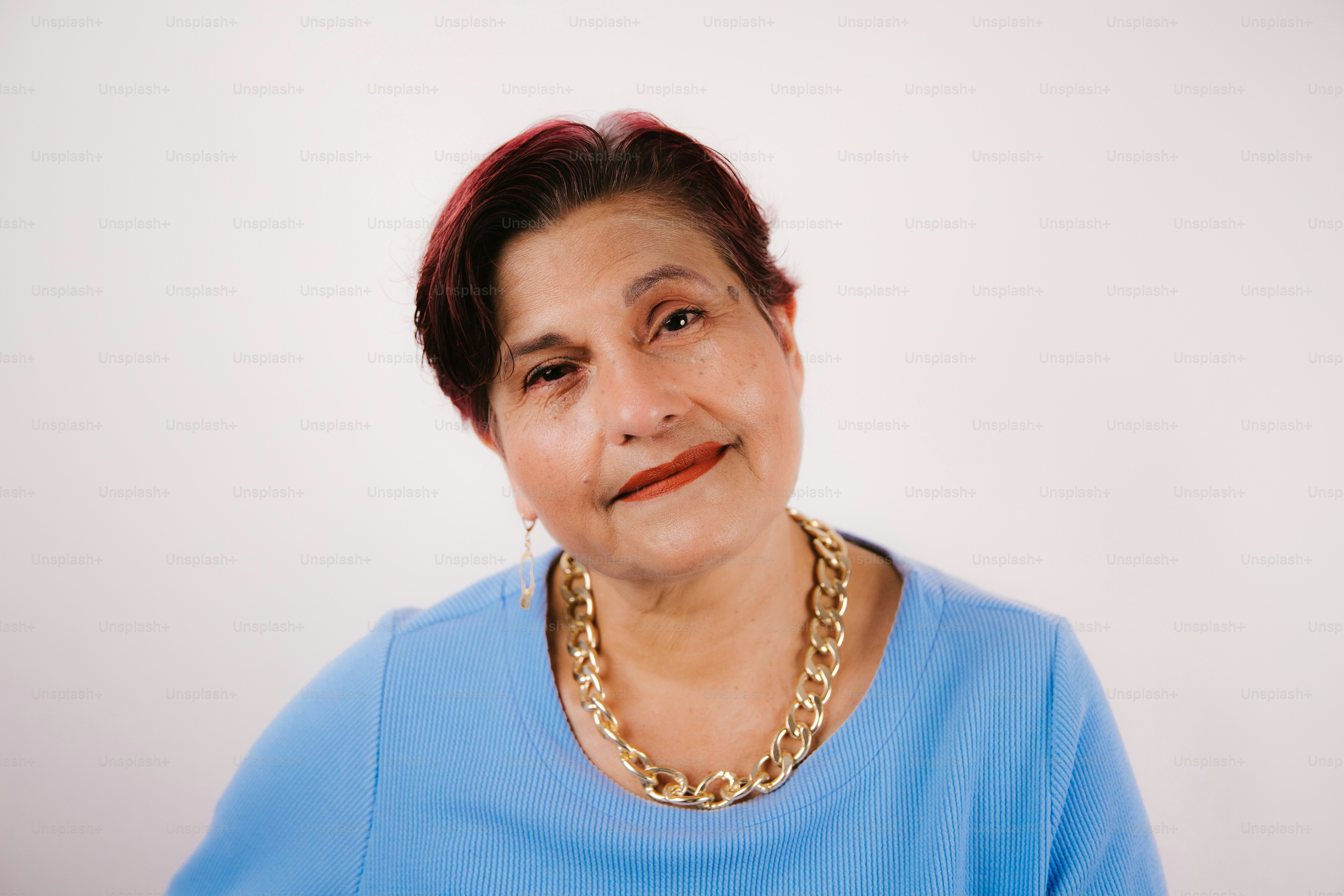 Elderly woman with short dark hair and gold necklace