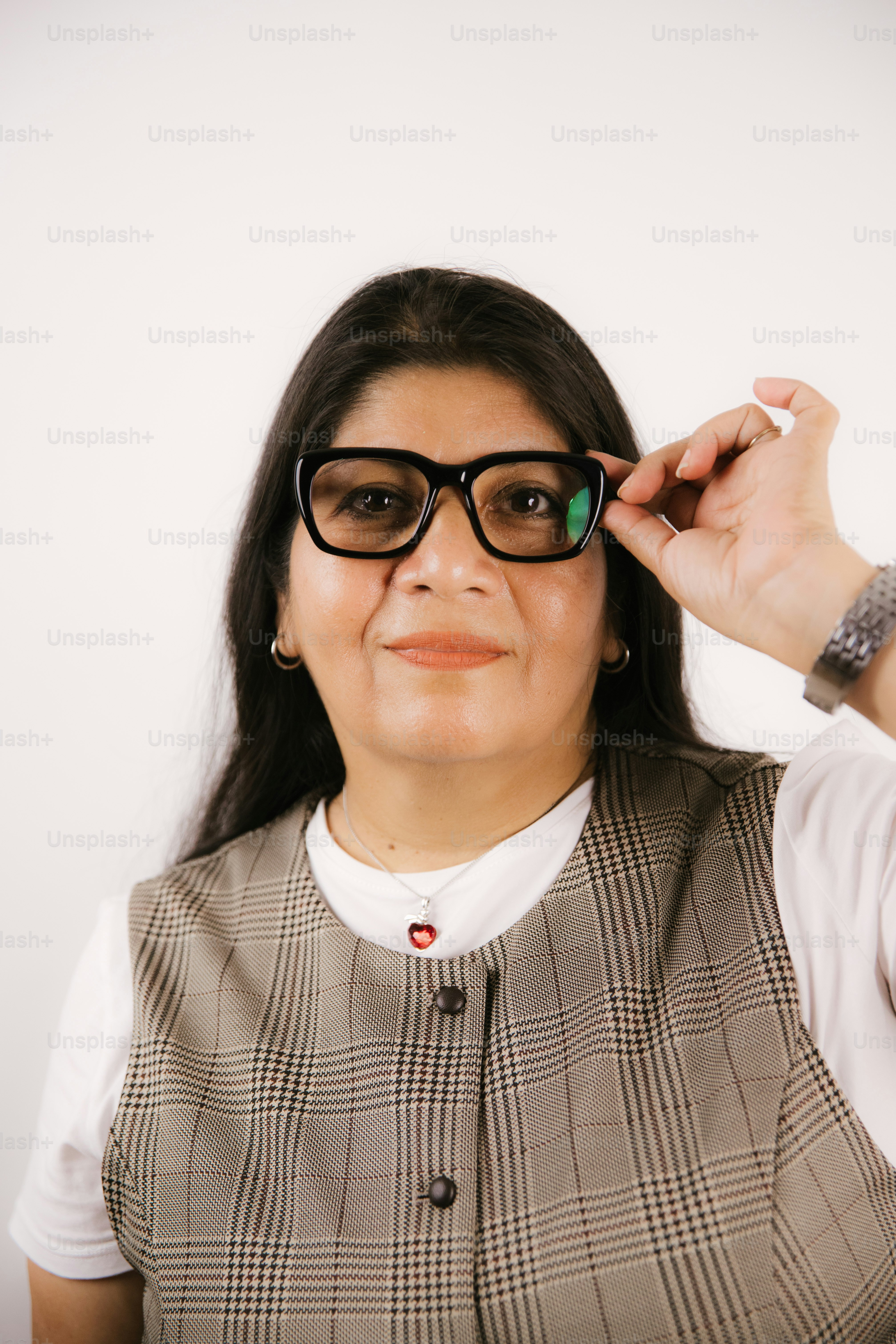 Woman adjusting her glasses against a white background.