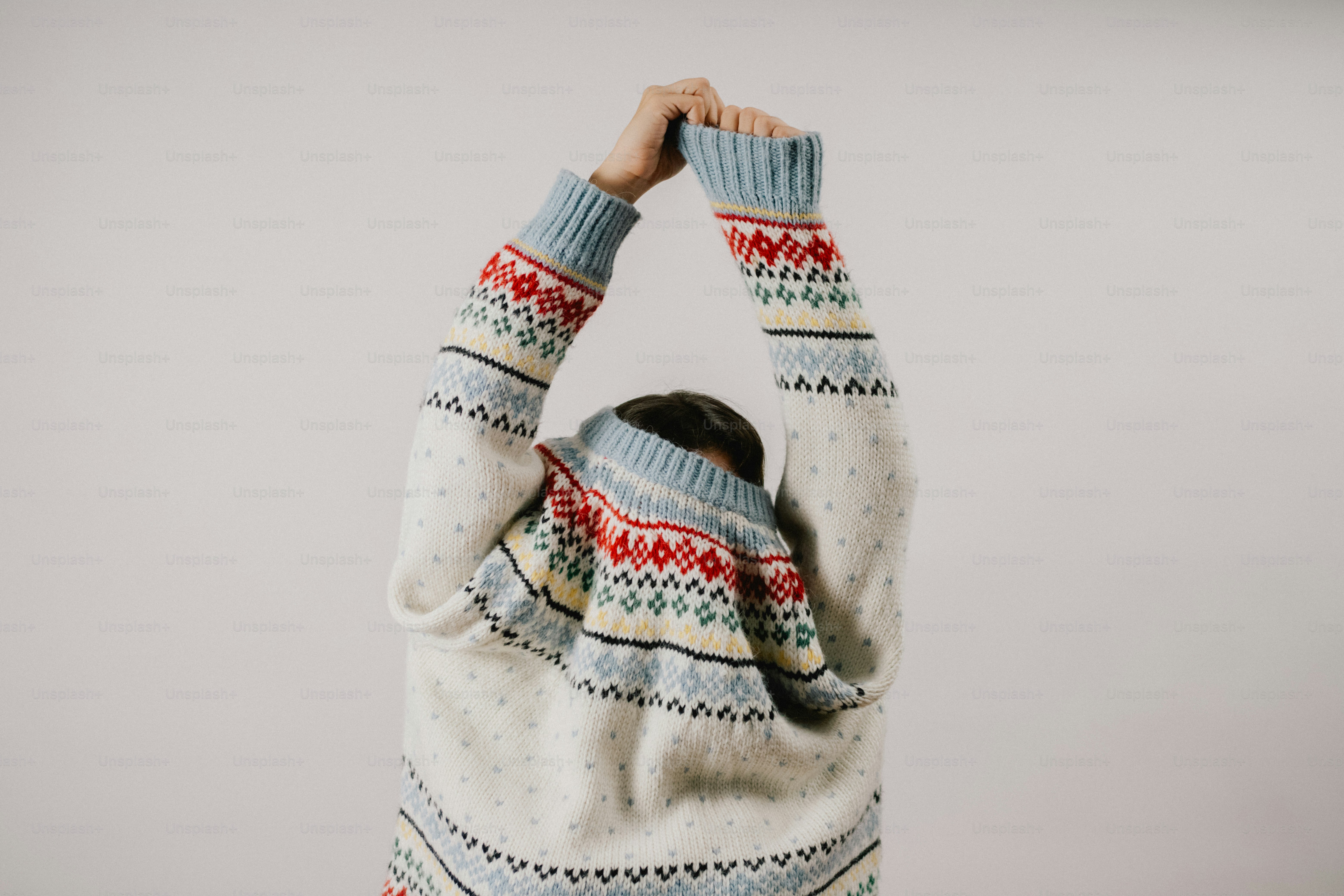 Person in patterned sweater stretching arms overhead