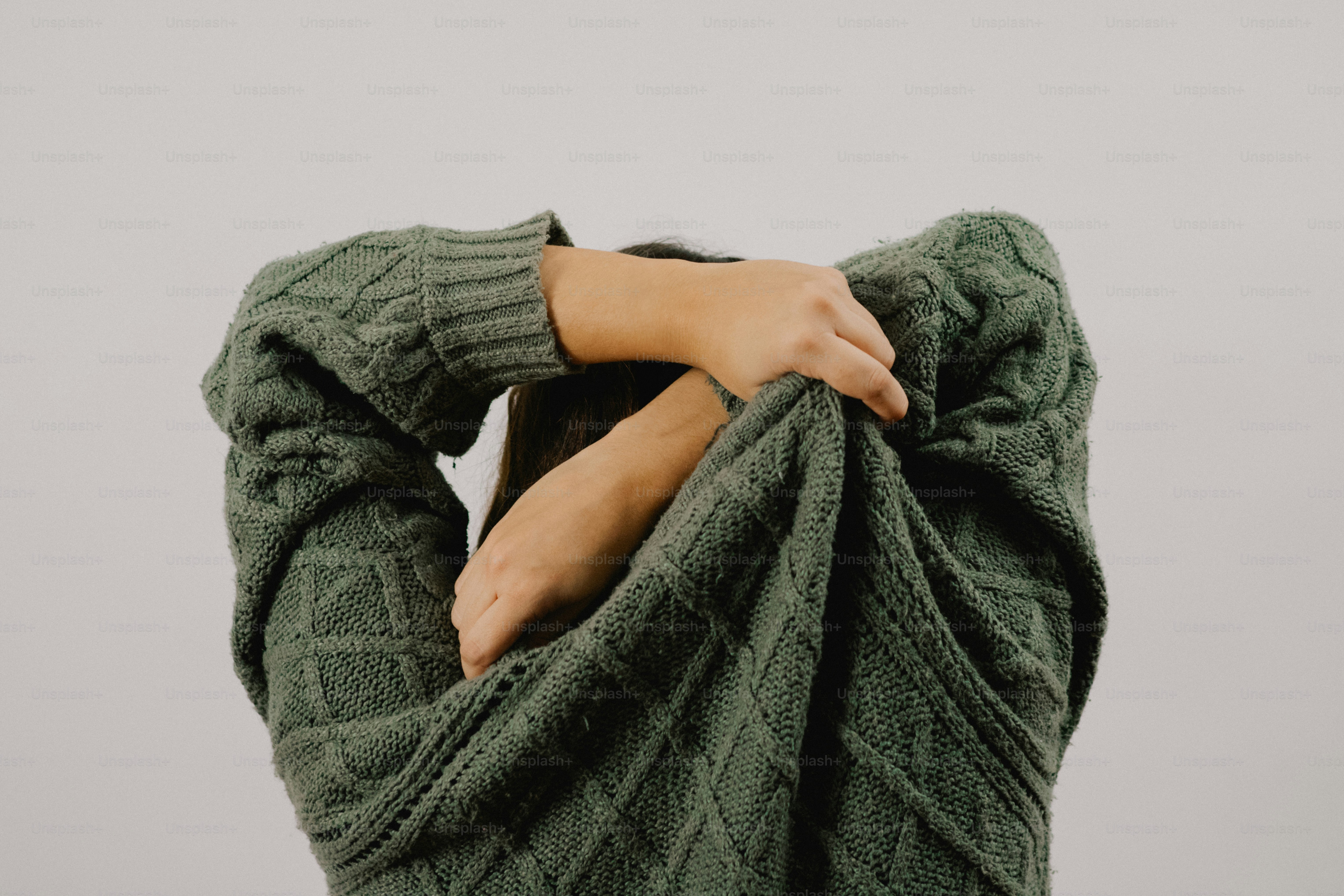 Person pulling on a chunky knit sweater