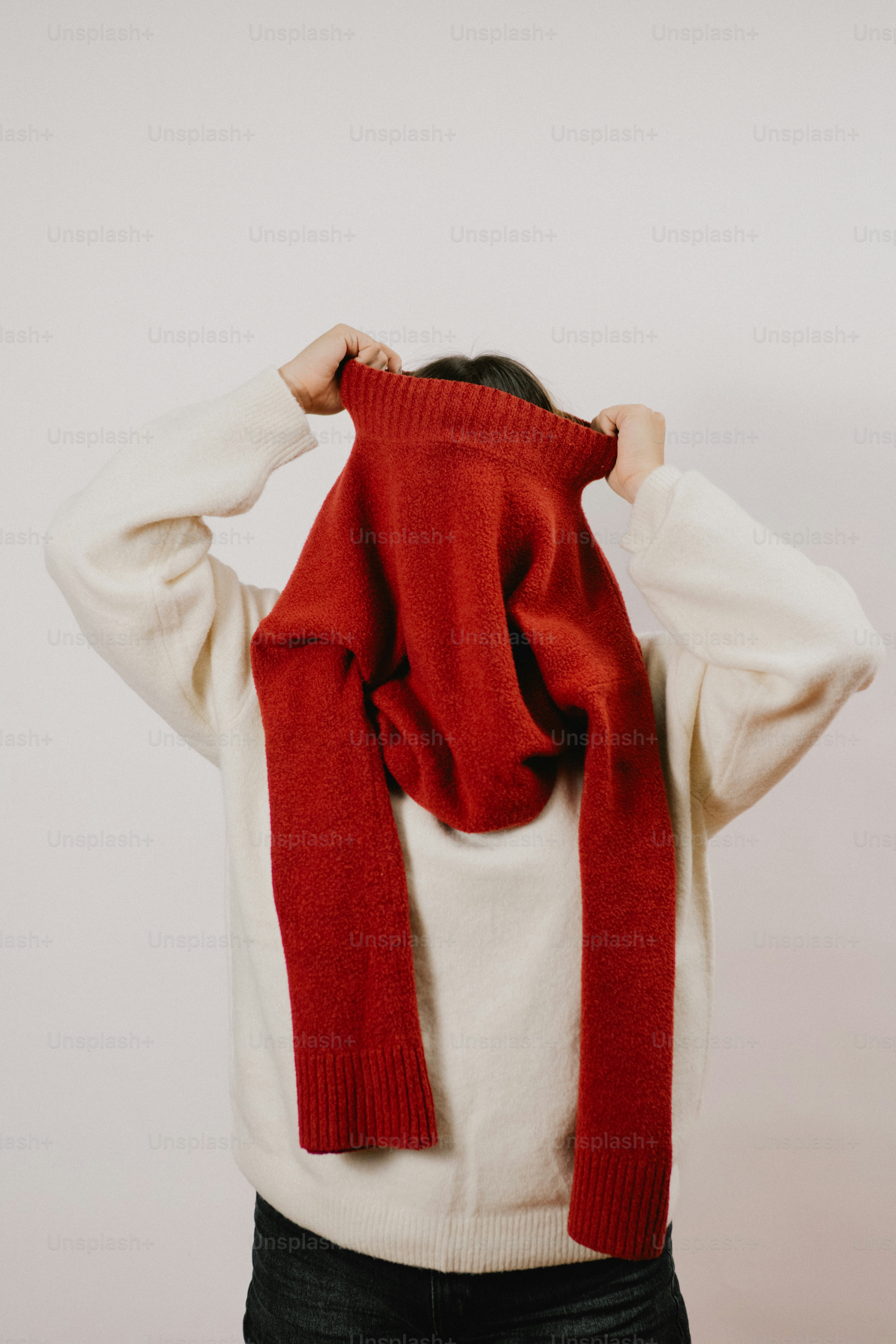 Person putting on a red sweater over their head