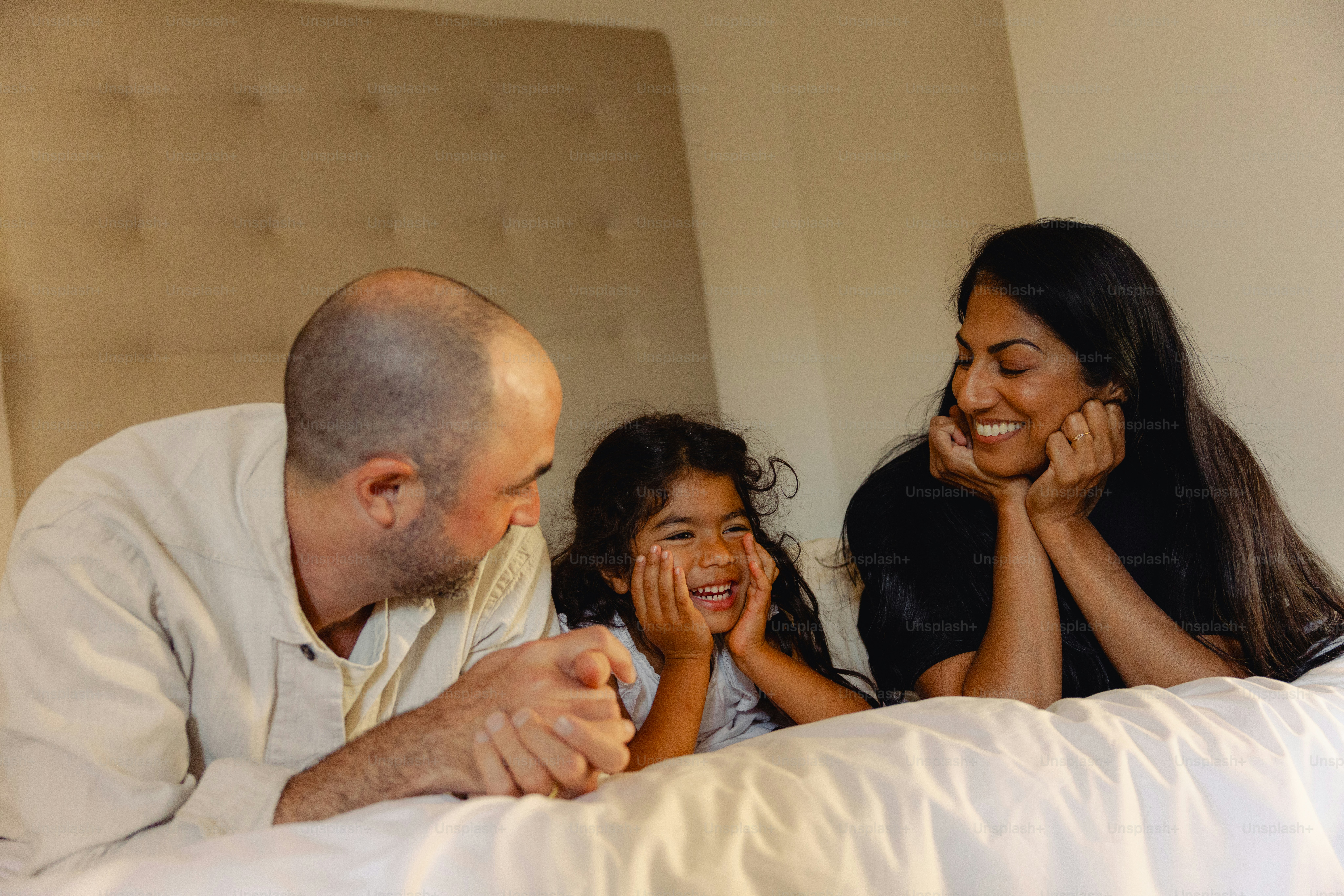 Familie liegt auf dem Bett, lächelt und redet