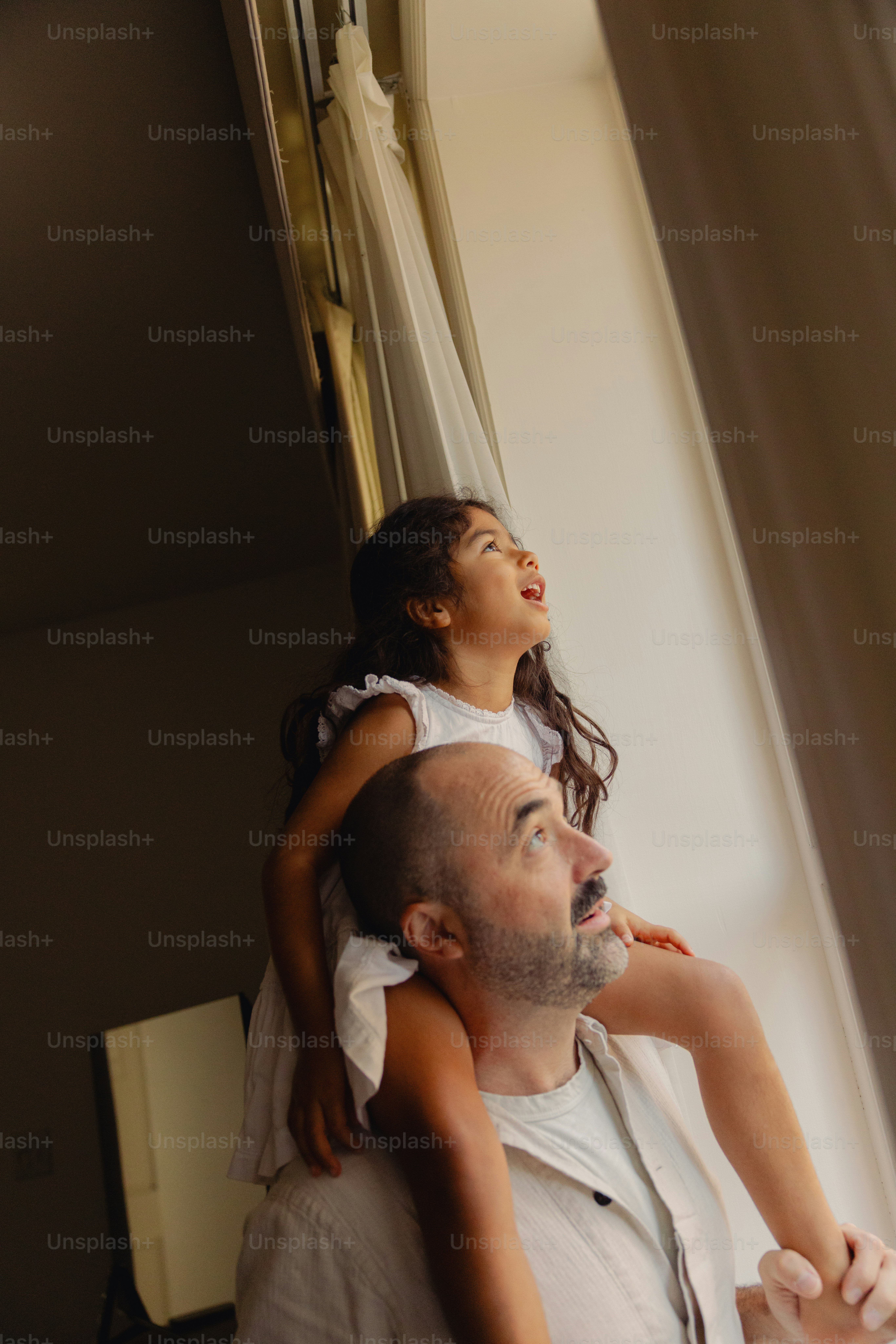 Vater trägt Tochter auf Schultern und schaut aus dem Fenster