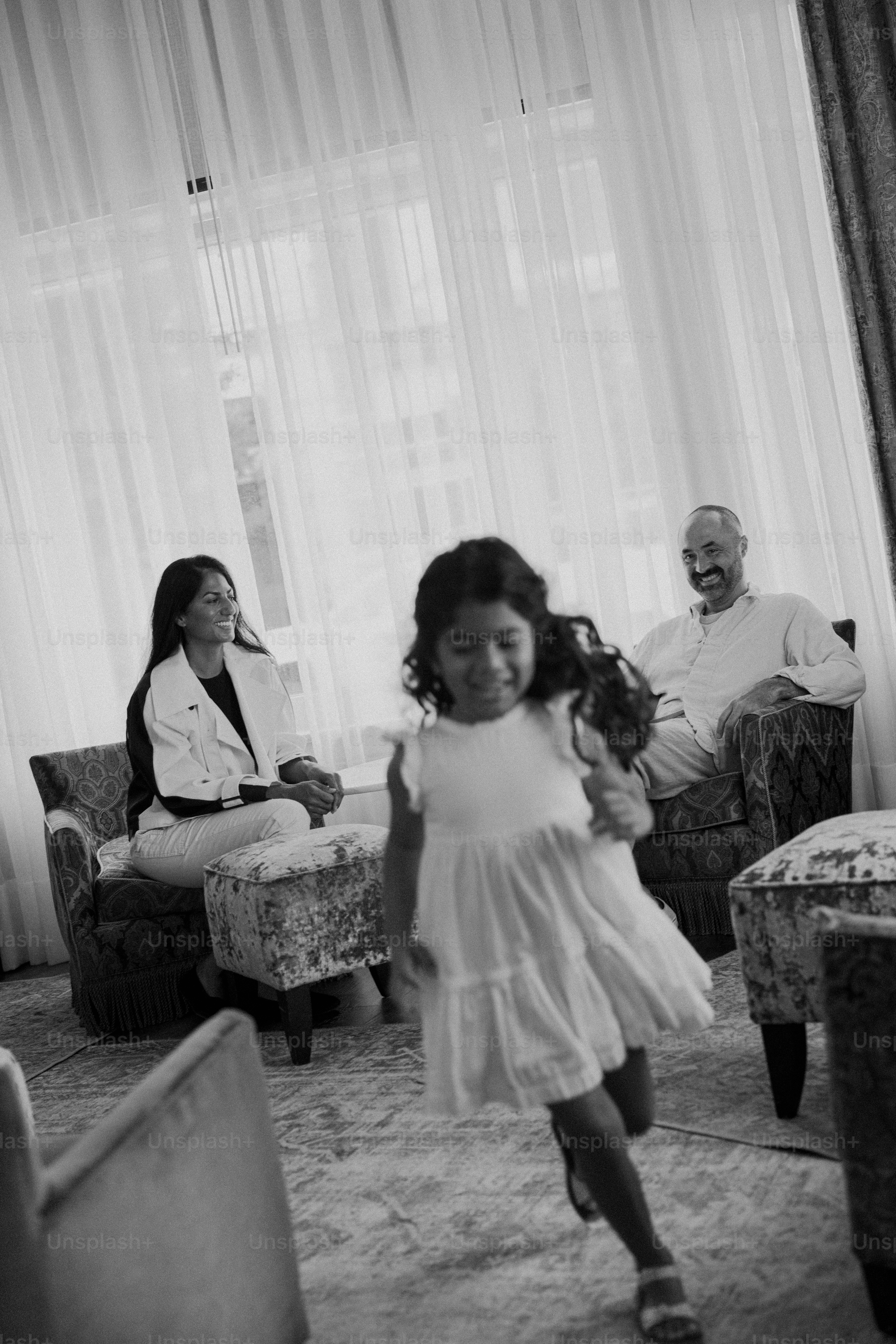 Ein junges Mädchen läuft auf die Kamera zu, während die Erwachsenen zuschauen.