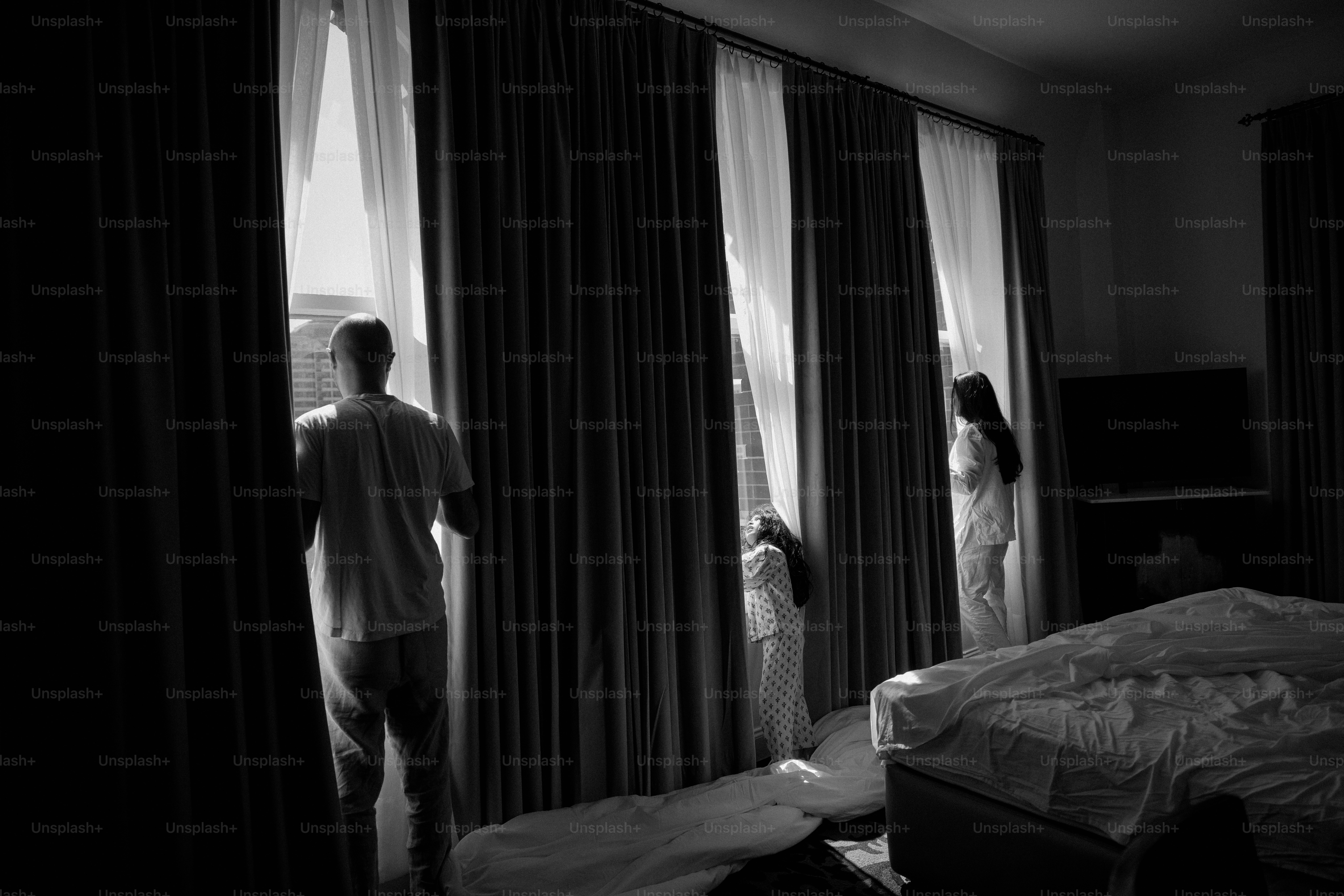 Paar, das im Morgengrauen aus den Fenstern eines Hotelzimmers schaut.