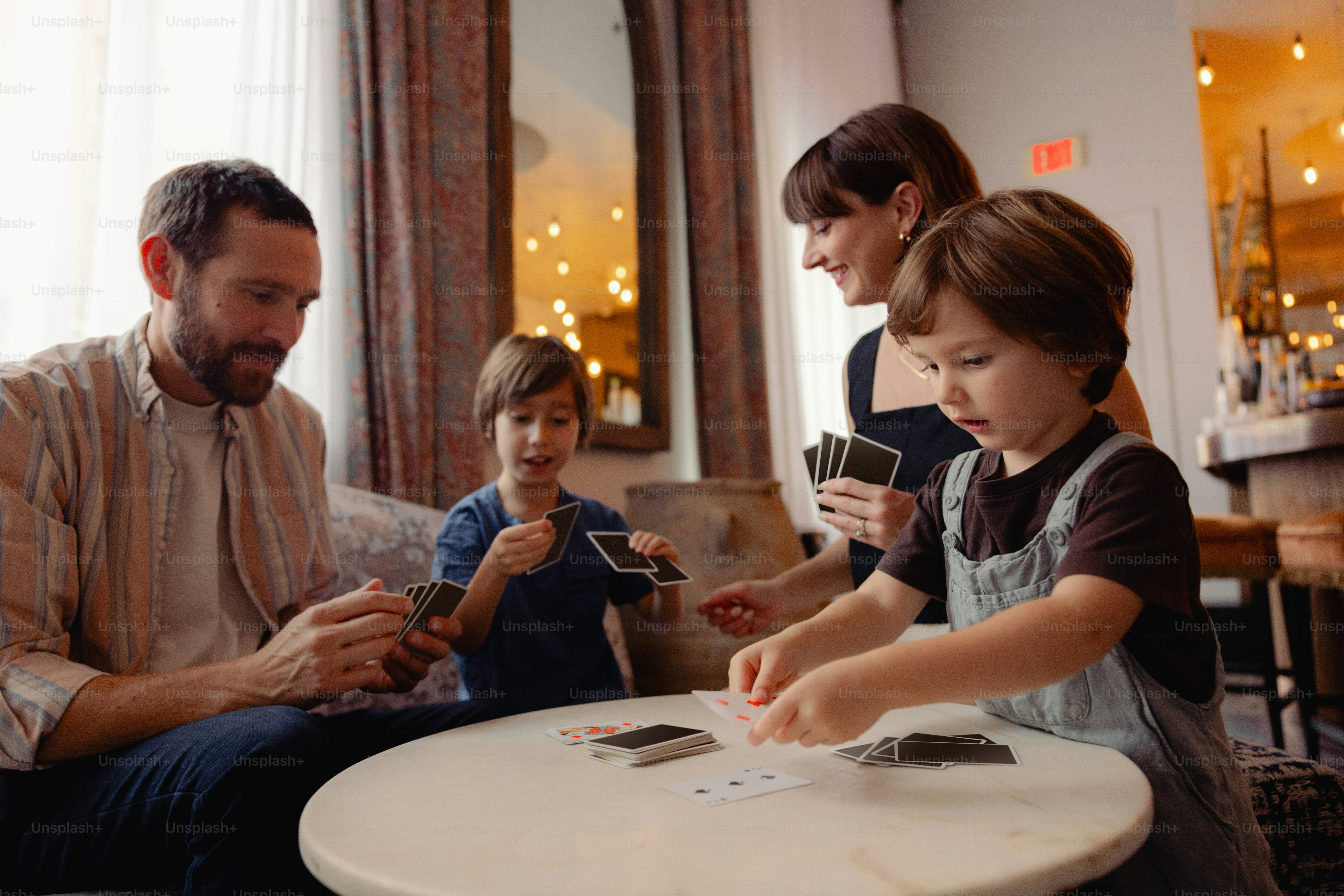 Family playing cards at a round table indoors.