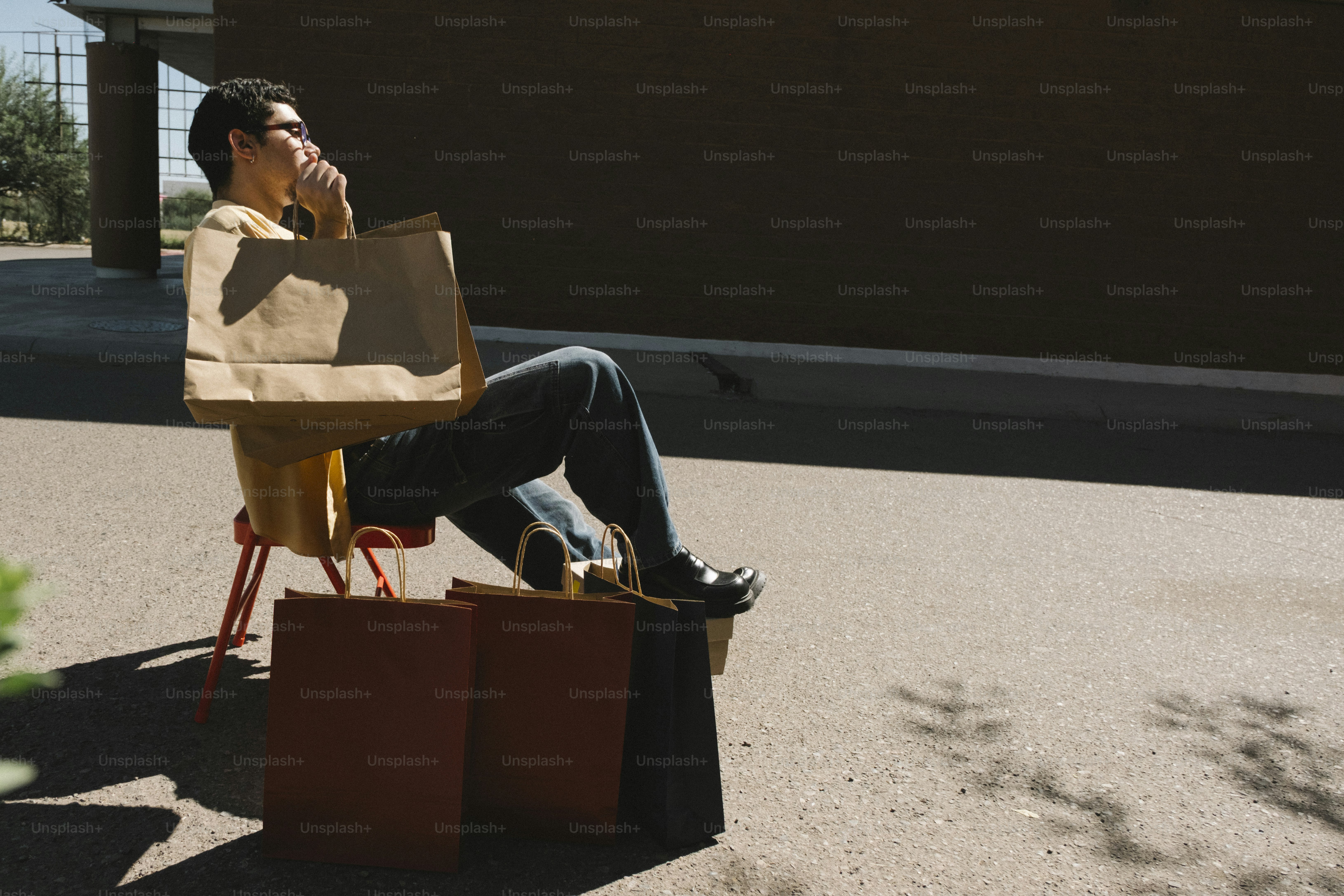 Man with shopping bags sits on chair outside