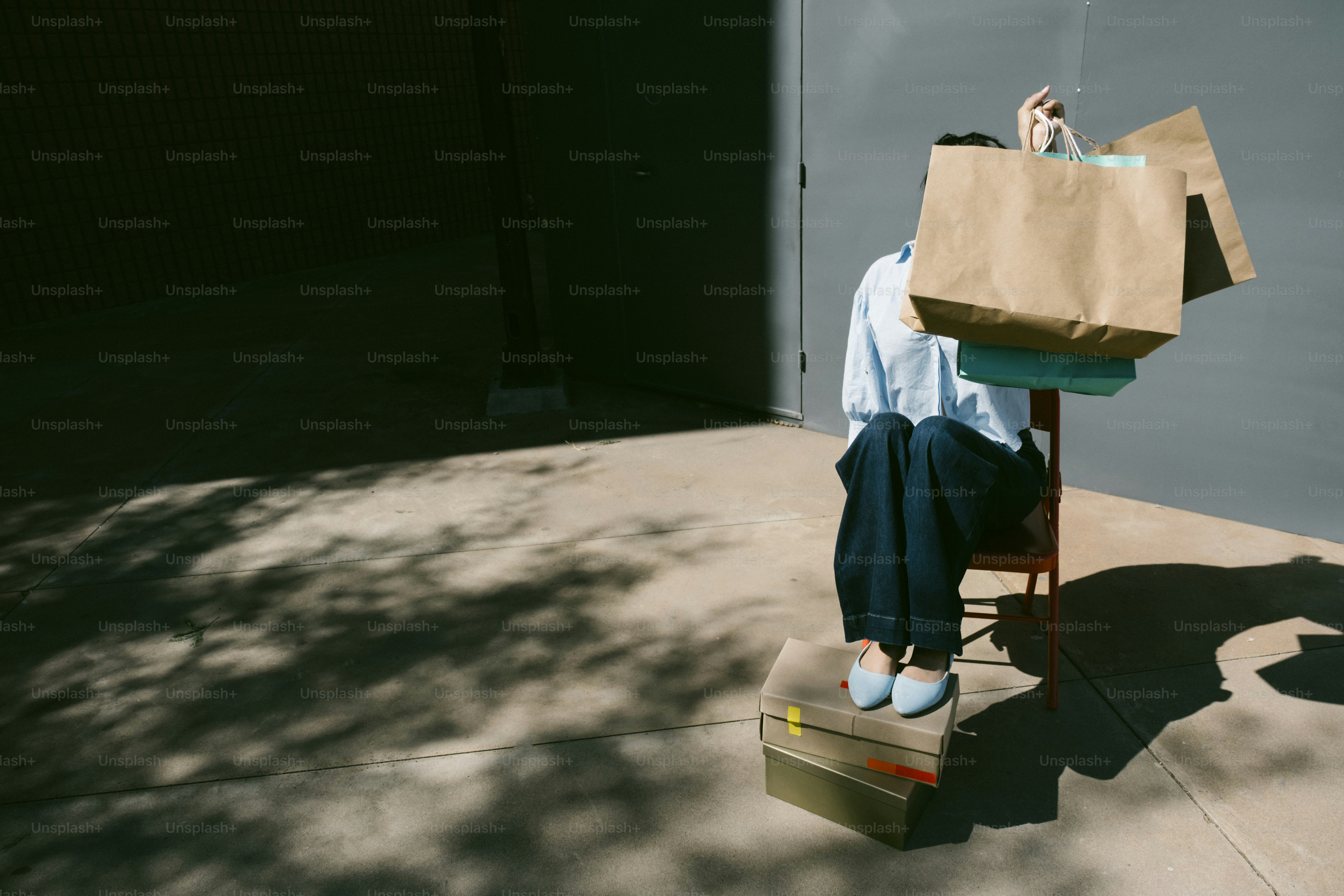 Person sitting with shopping bags obscuring face