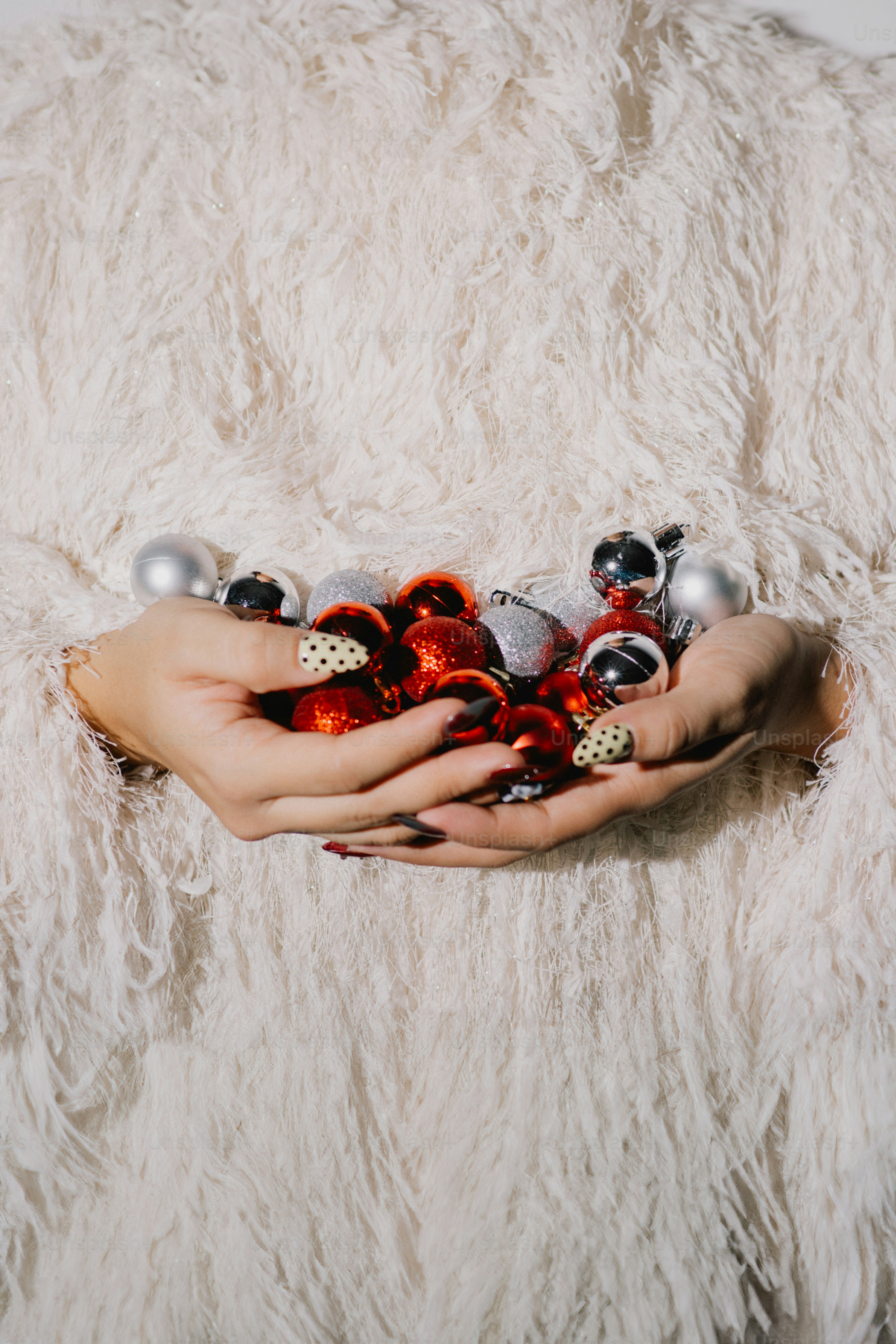 빨간색과 은색의 크리스마스 장식품을 들고 있는 손