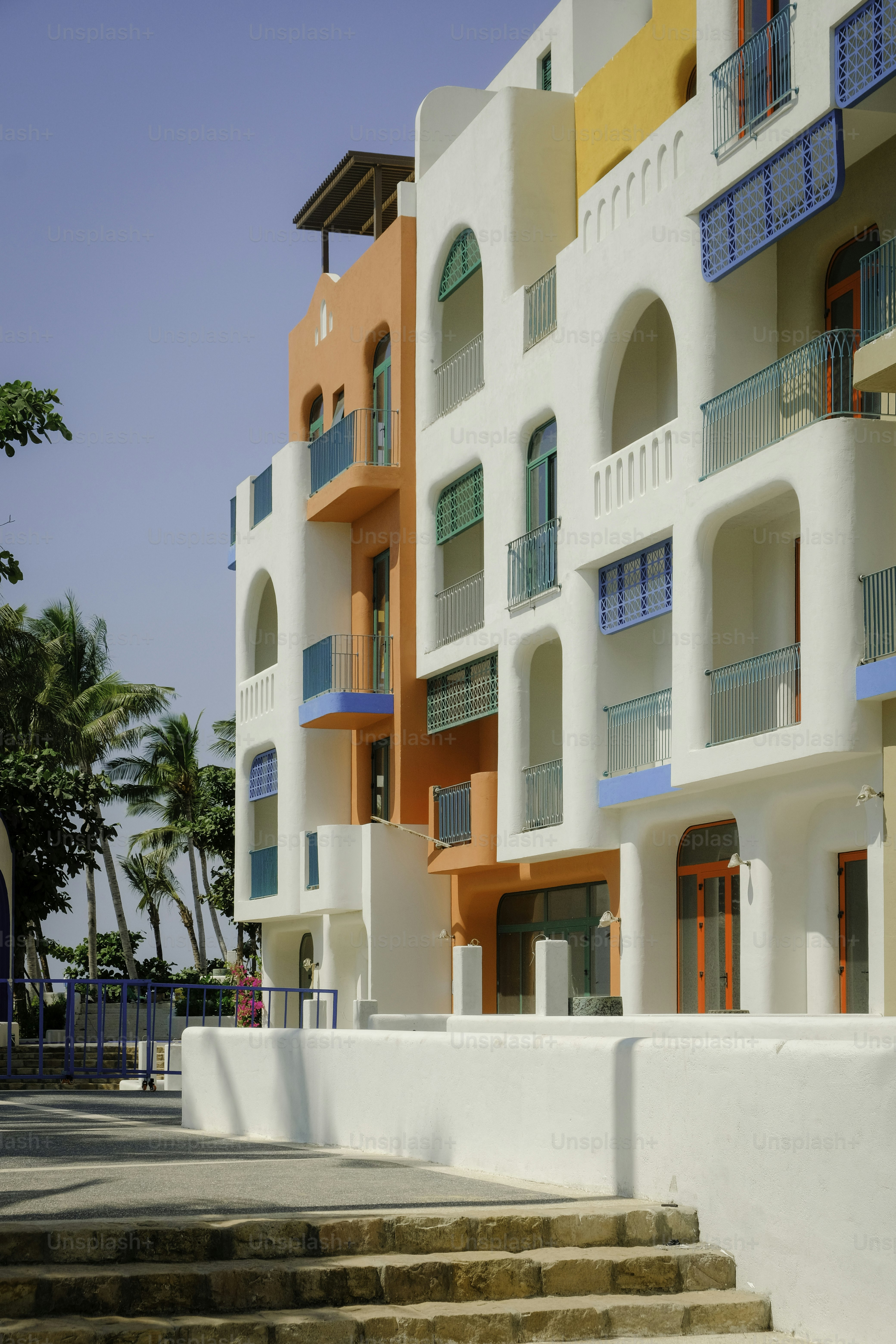 Bâtiment coloré de style méditerranéen avec balcons et fenêtres.