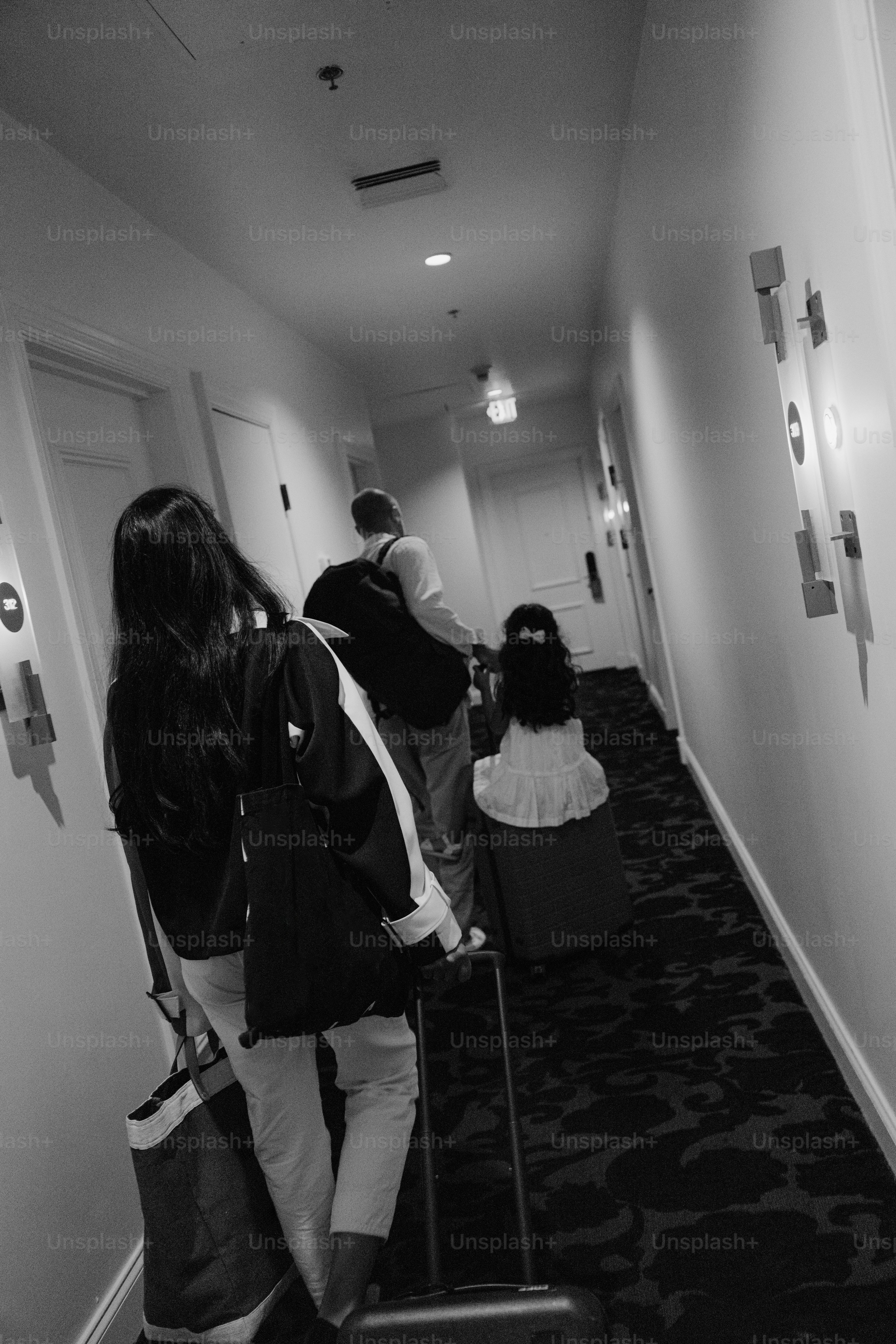 Familie geht mit Gepäck einen Hotelflur entlang