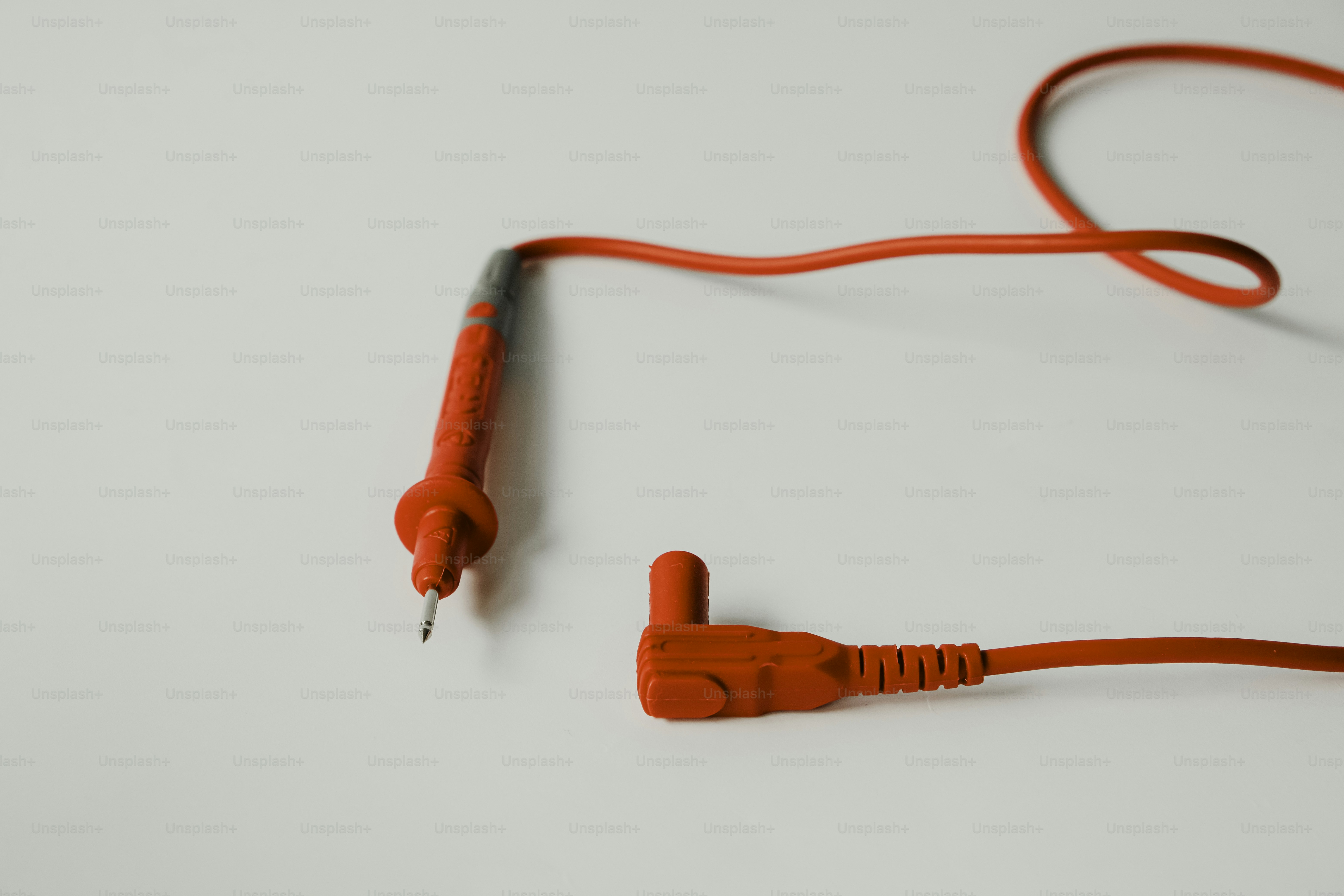 Two red electrical test leads on white surface