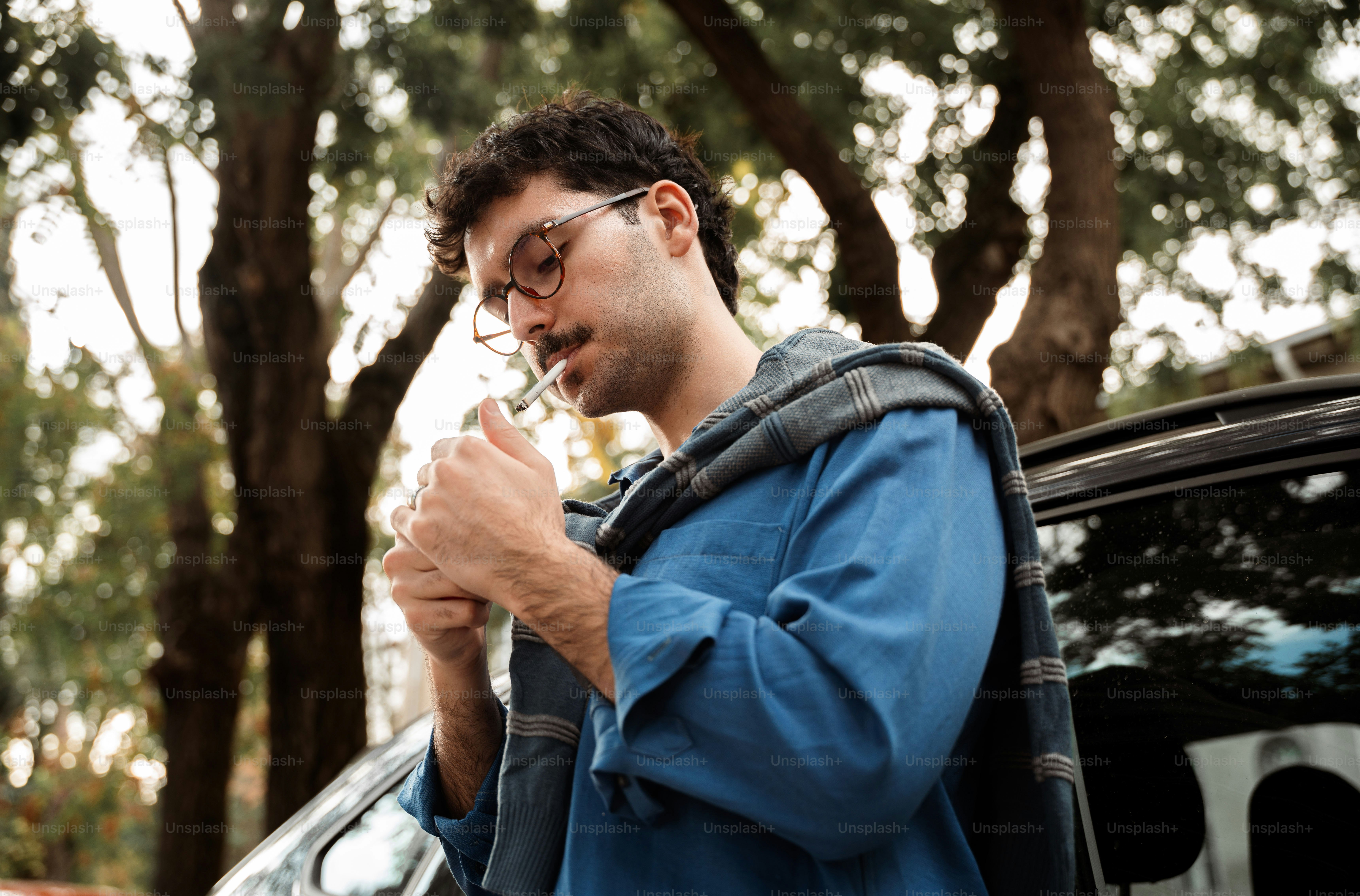 Man lighting a cigarette outdoors near a car