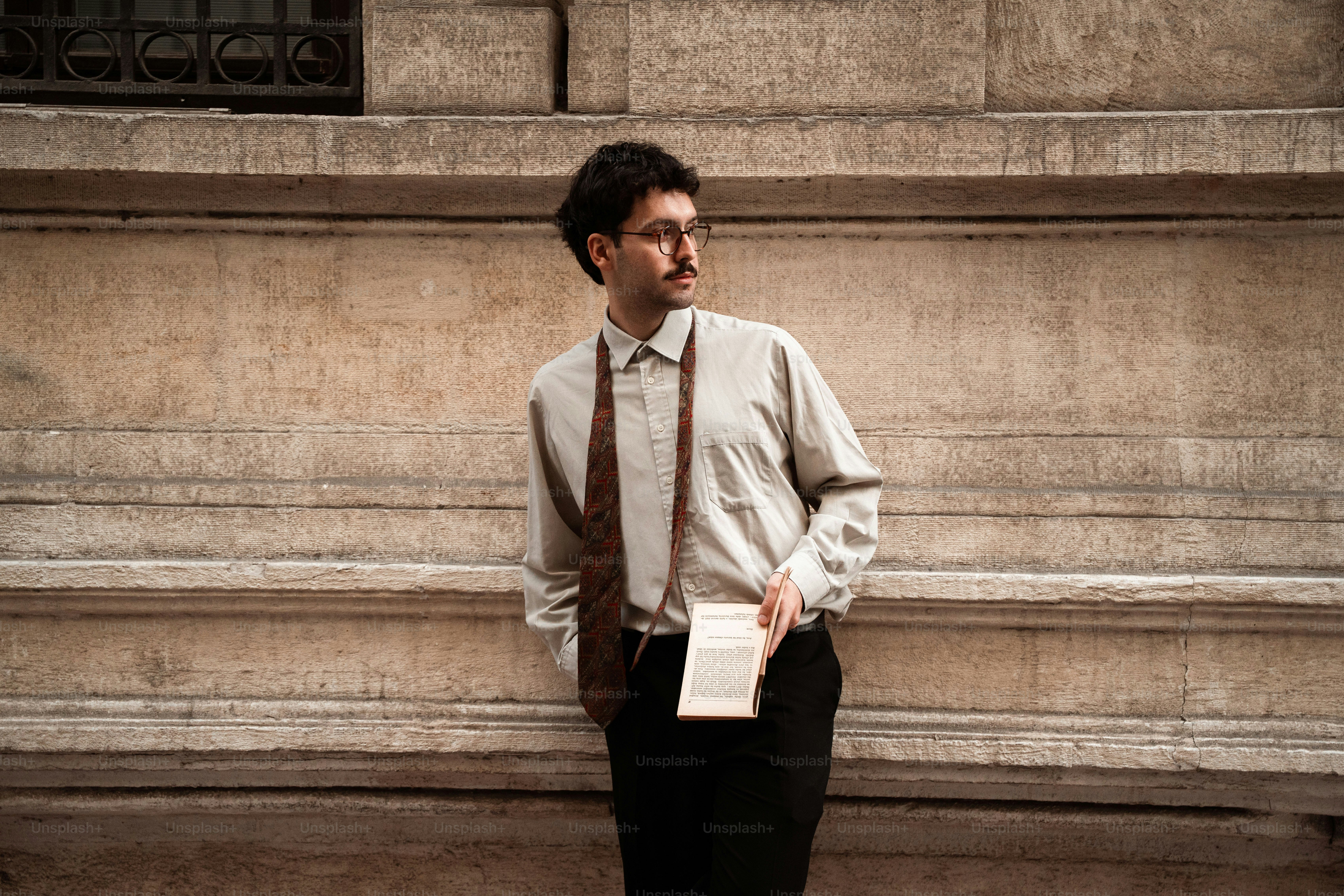 Man in shirt and tie holding a book outdoors