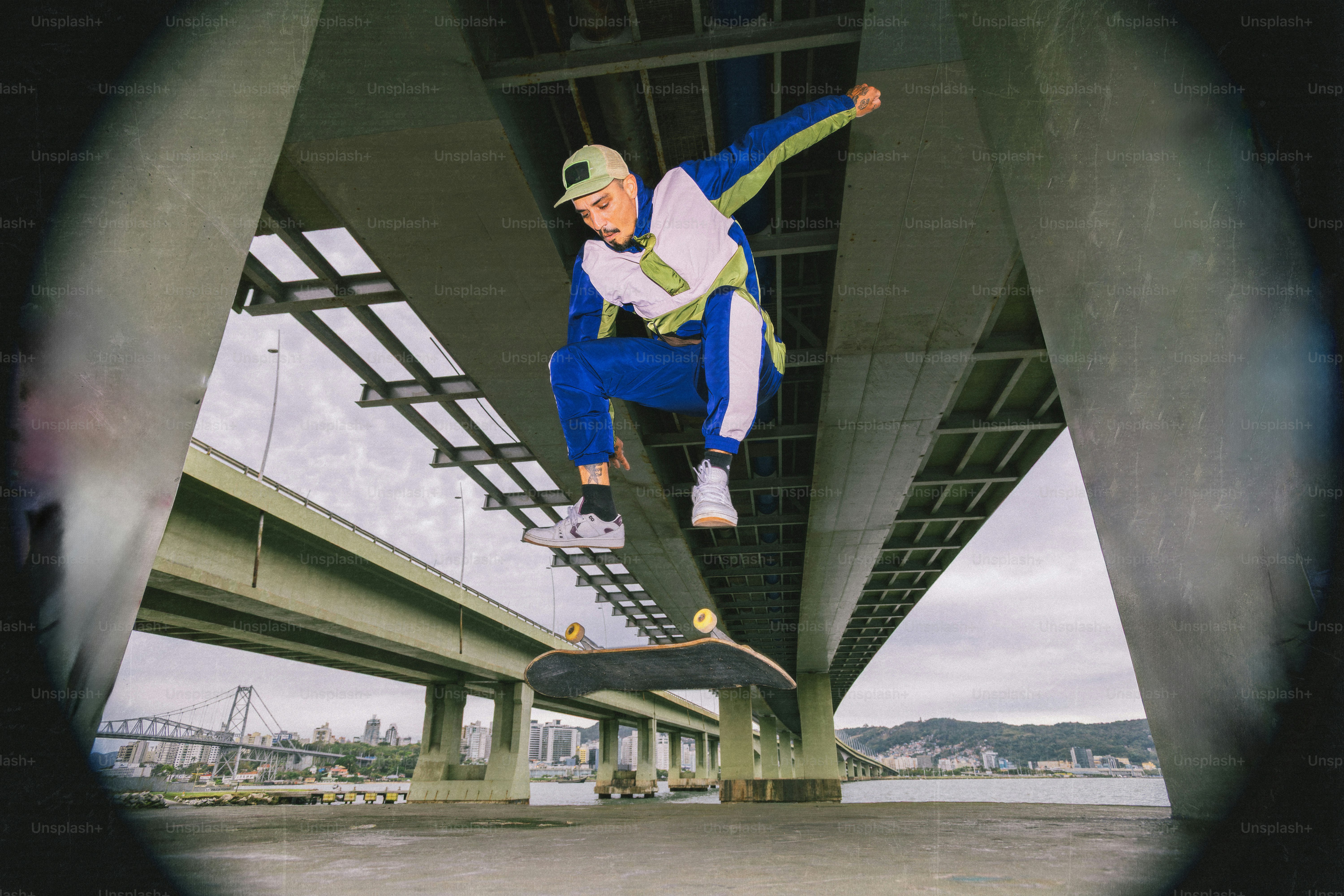 Skateboarder che esegue un trick sotto un ponte.
