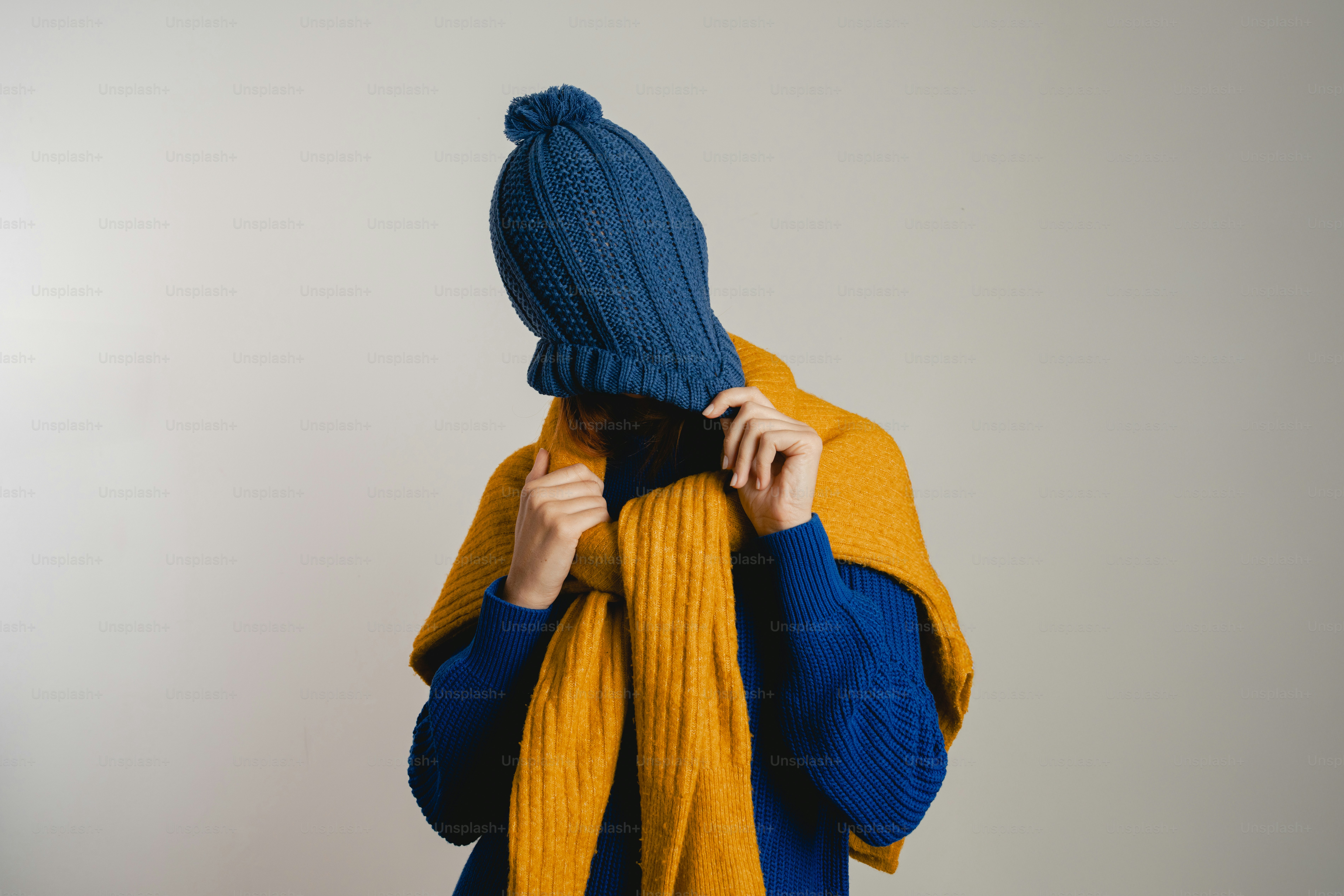 Person wearing a blue hat and yellow scarf