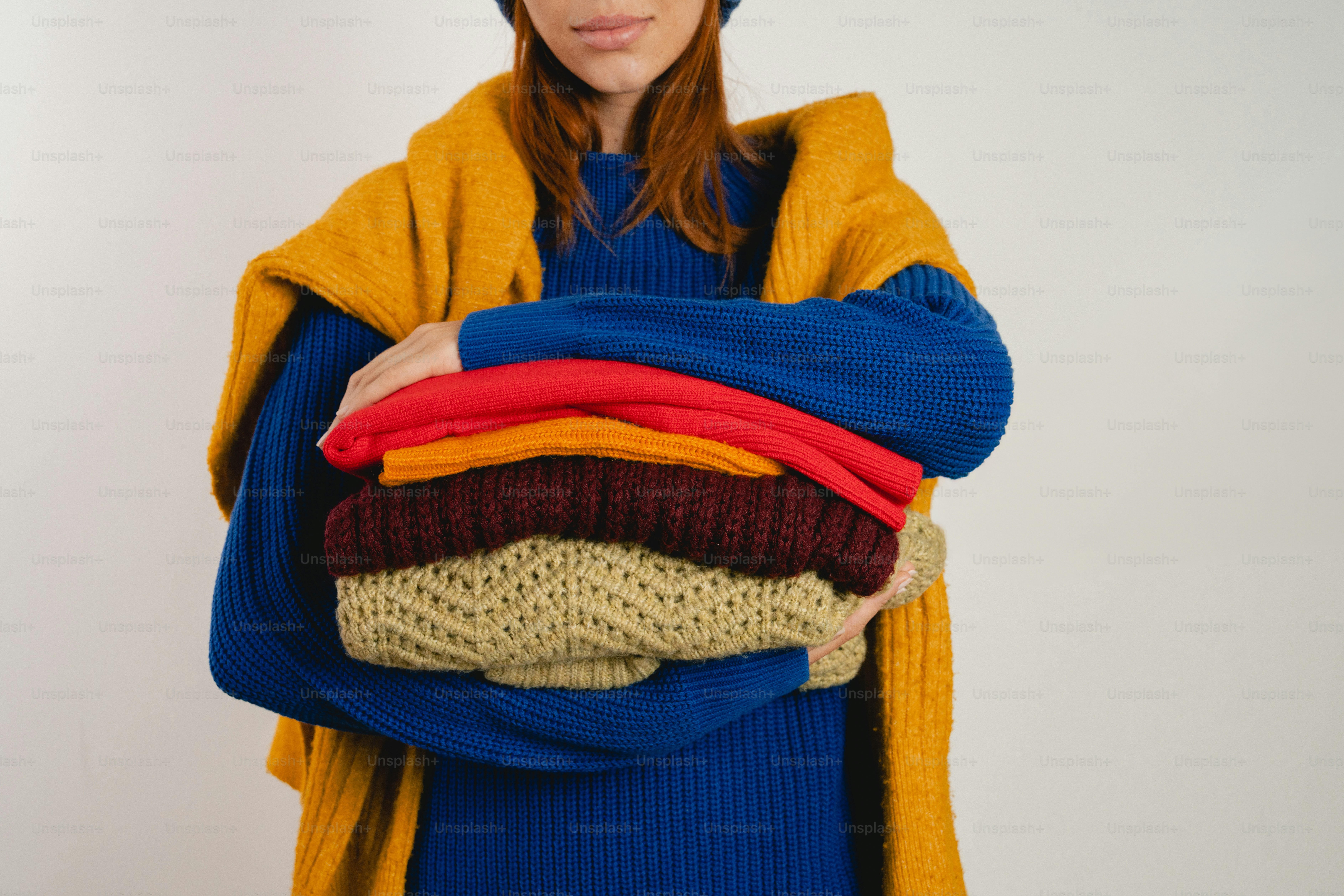 Woman holding a stack of colorful folded sweaters