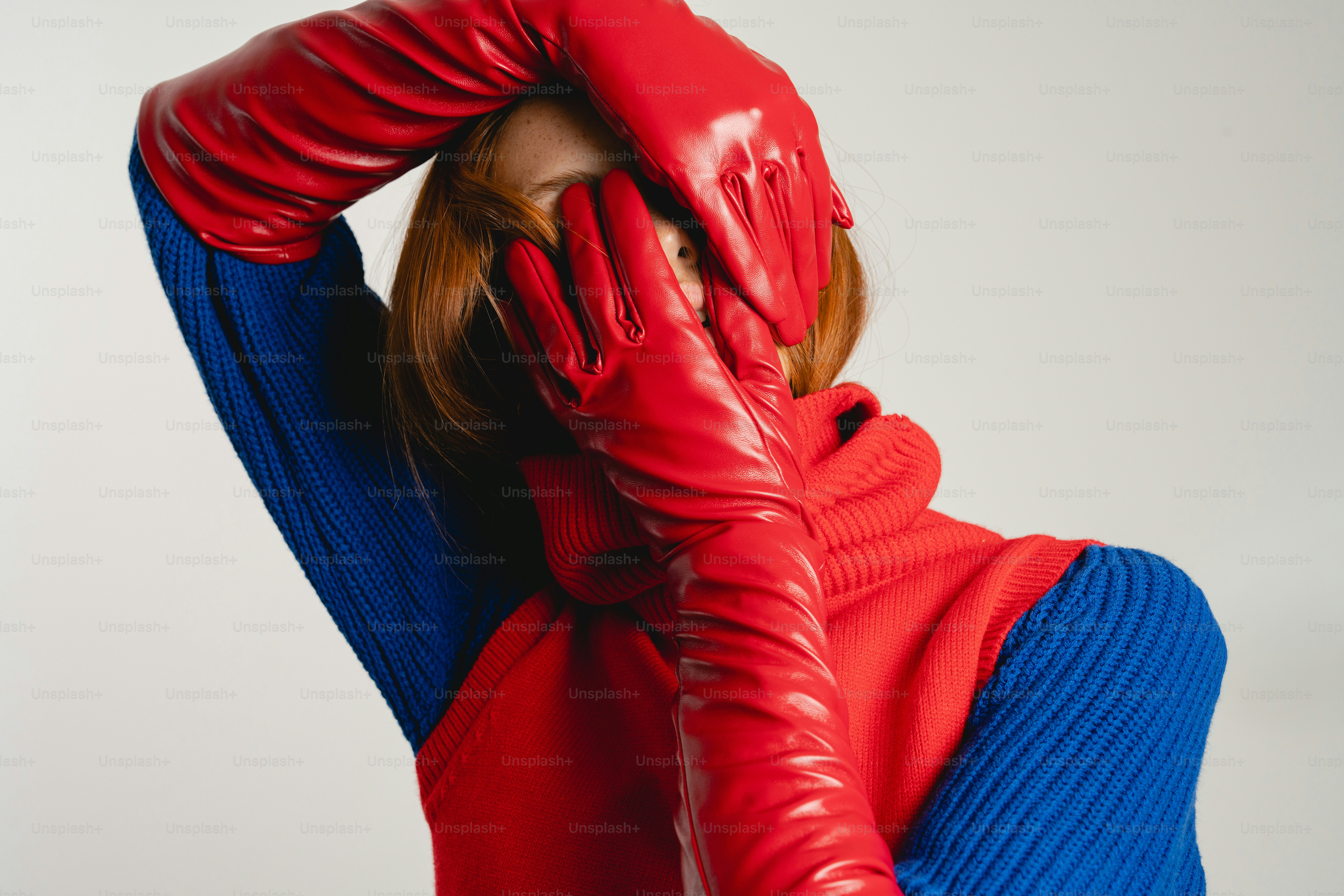 Woman in red gloves covers face with hands