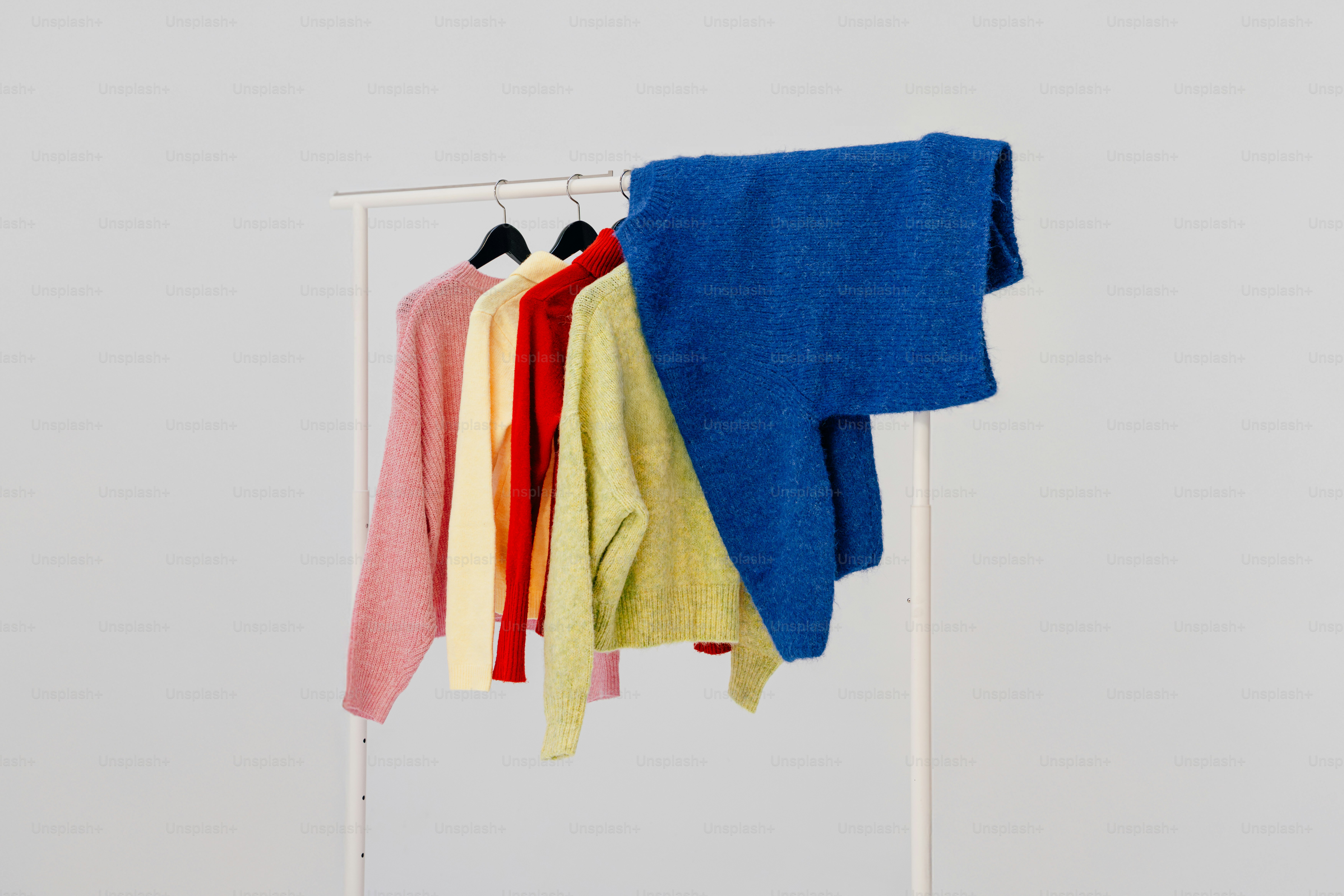 Four colorful sweaters hanging on a rack.