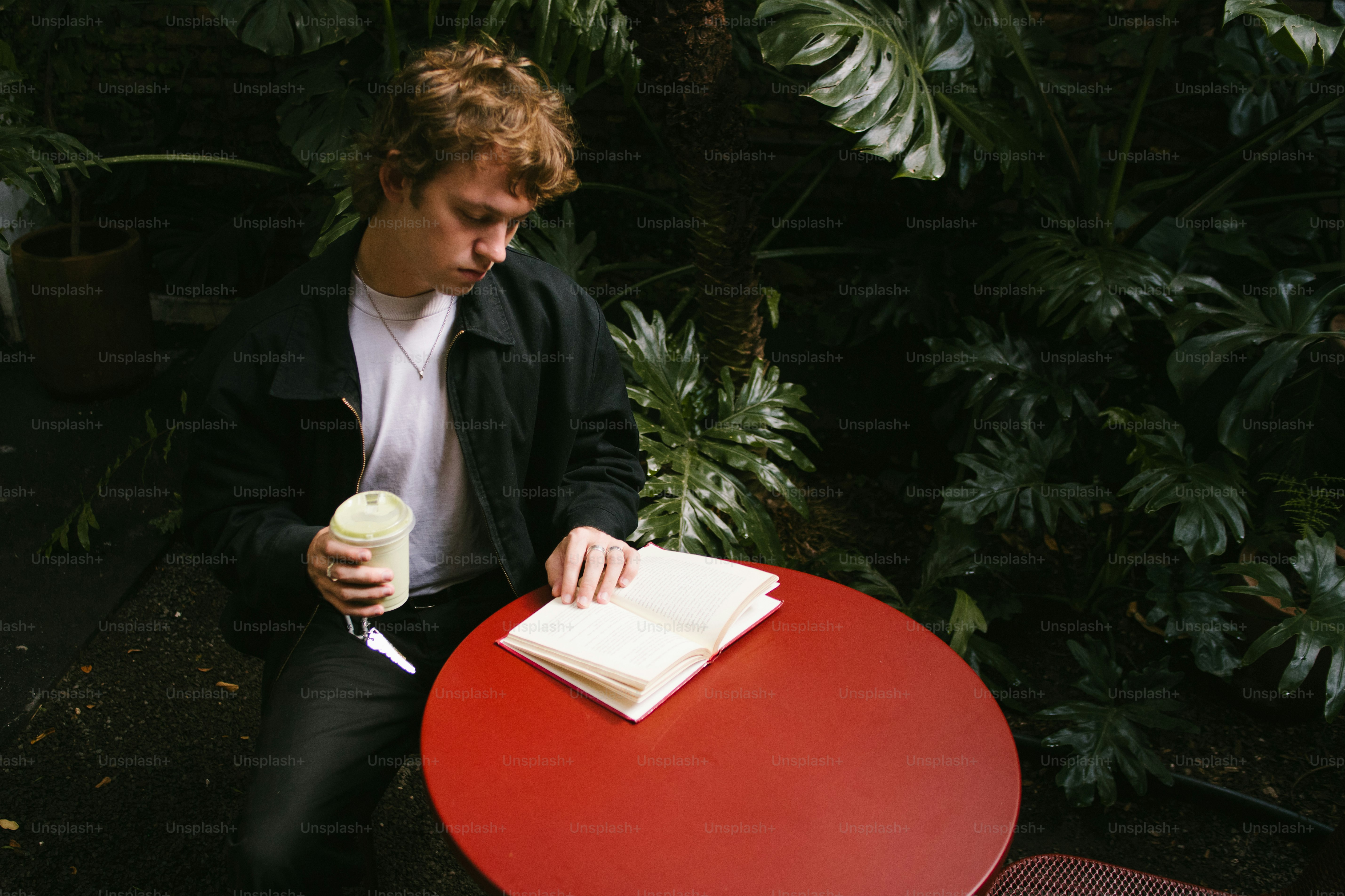 Man with drink and book at red table