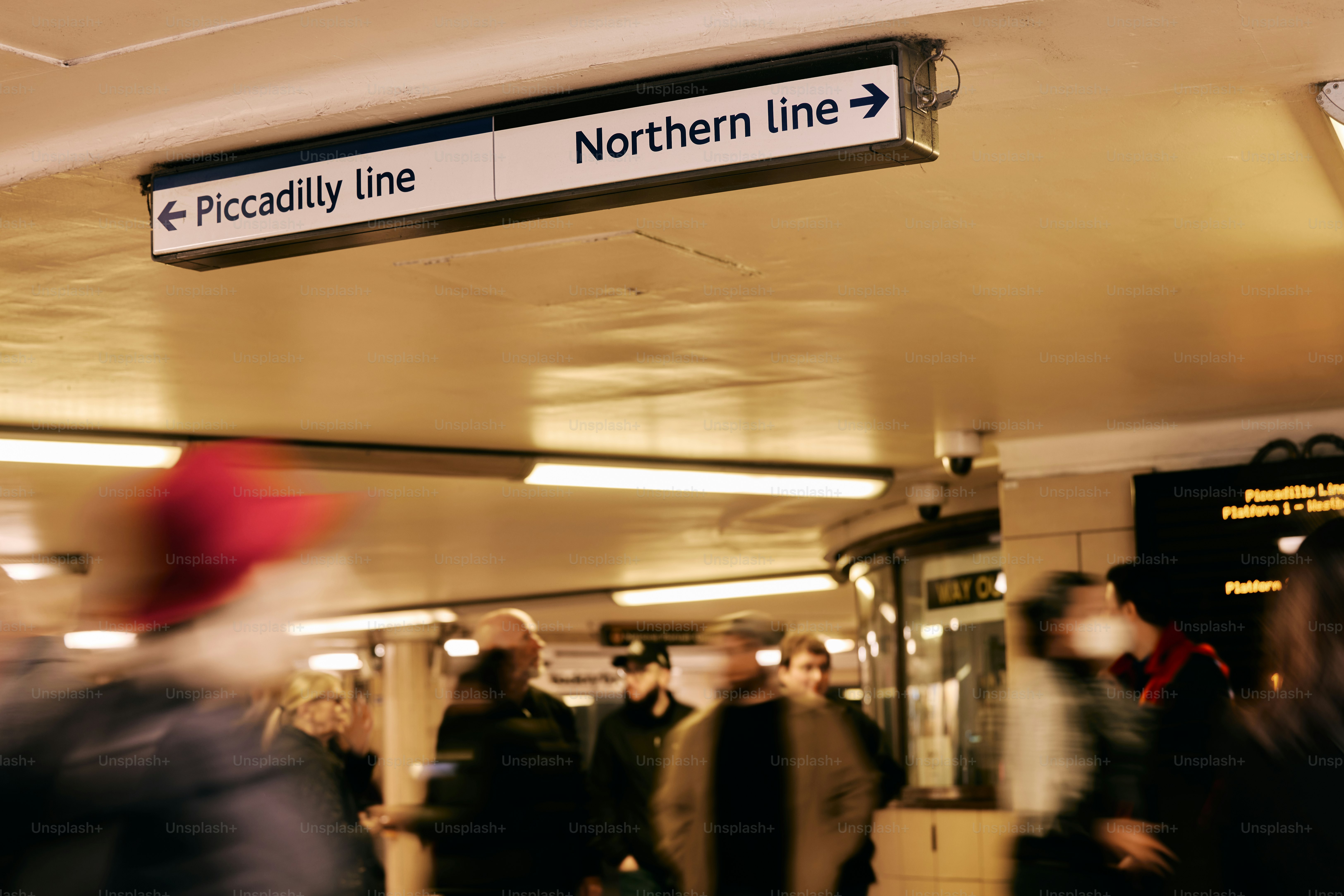 Menschen, die in einer U-Bahn-Station mit Schildern gehen.