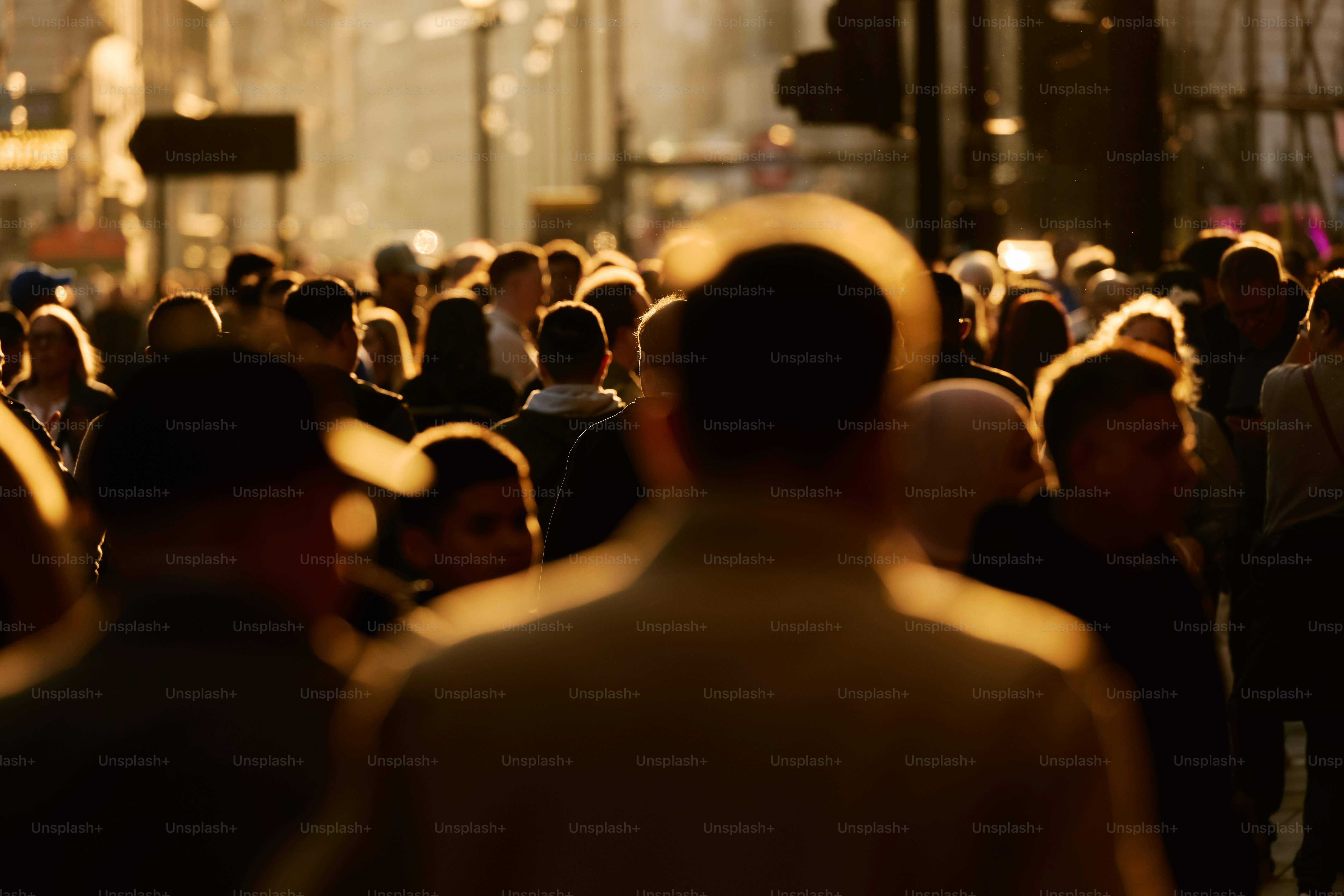 Crowd of people walking in city street at dusk.
