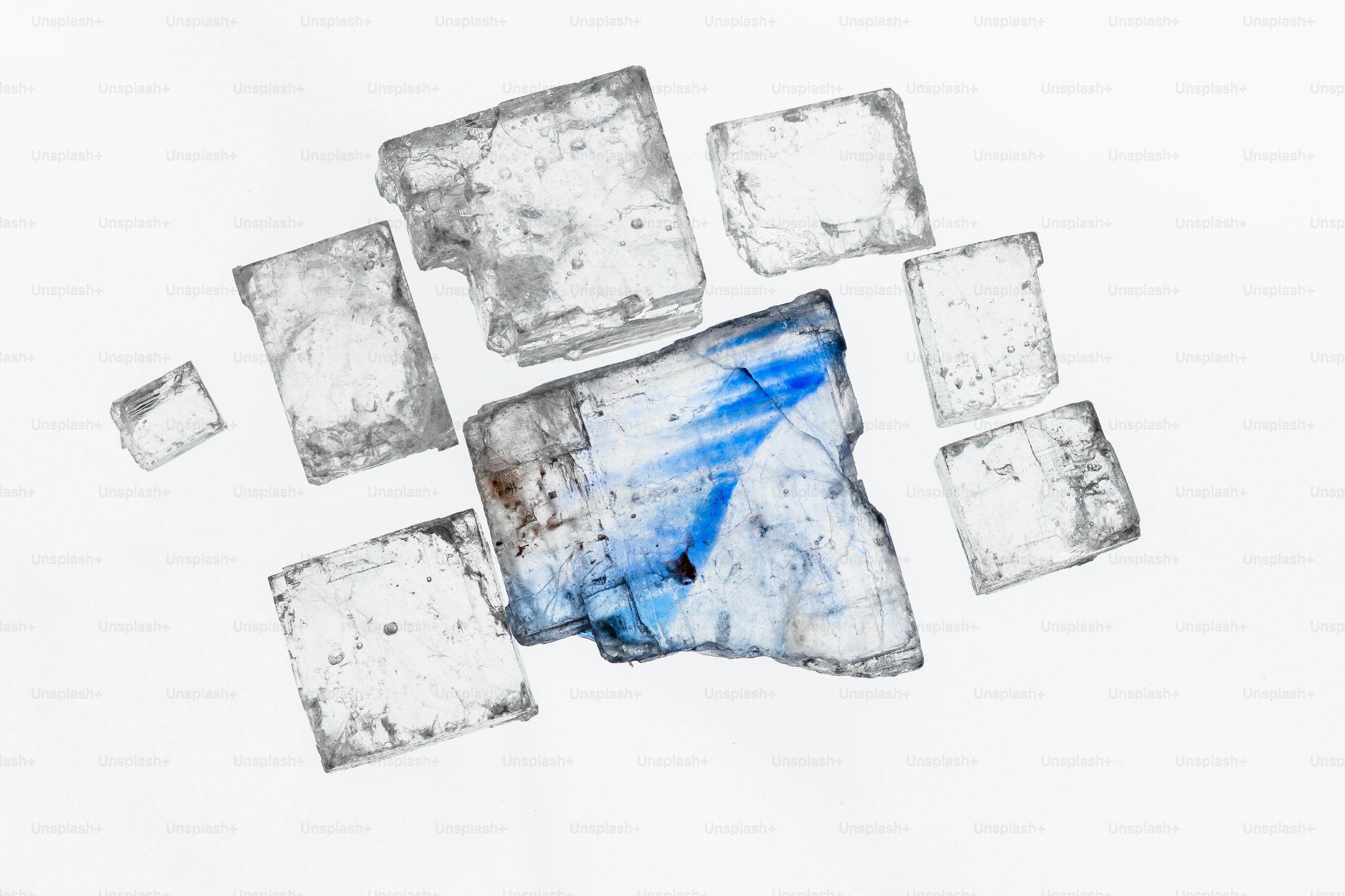 Cubic salt crystals with blue streaks on white background