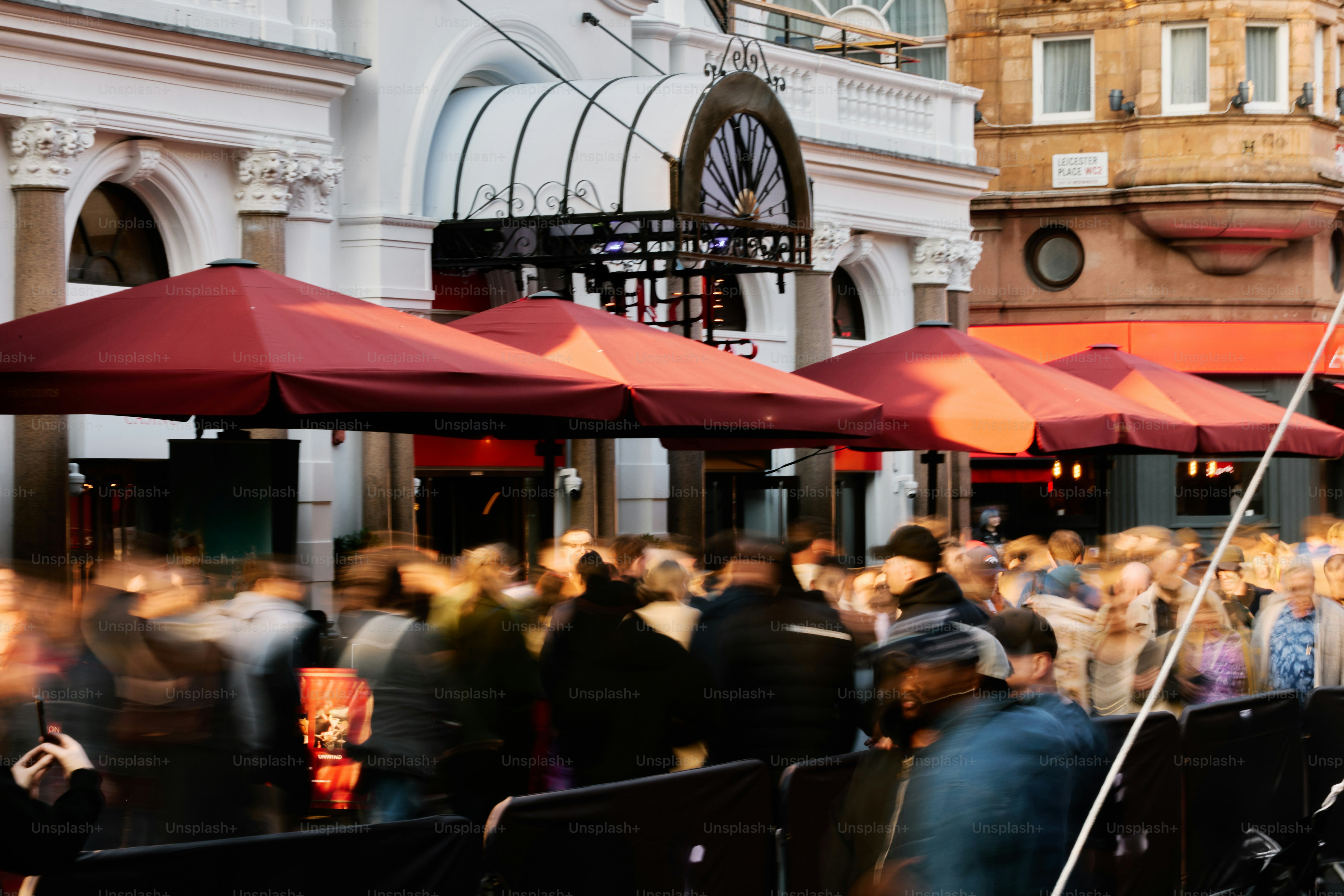 People gathered outside a grand building with umbrellas.