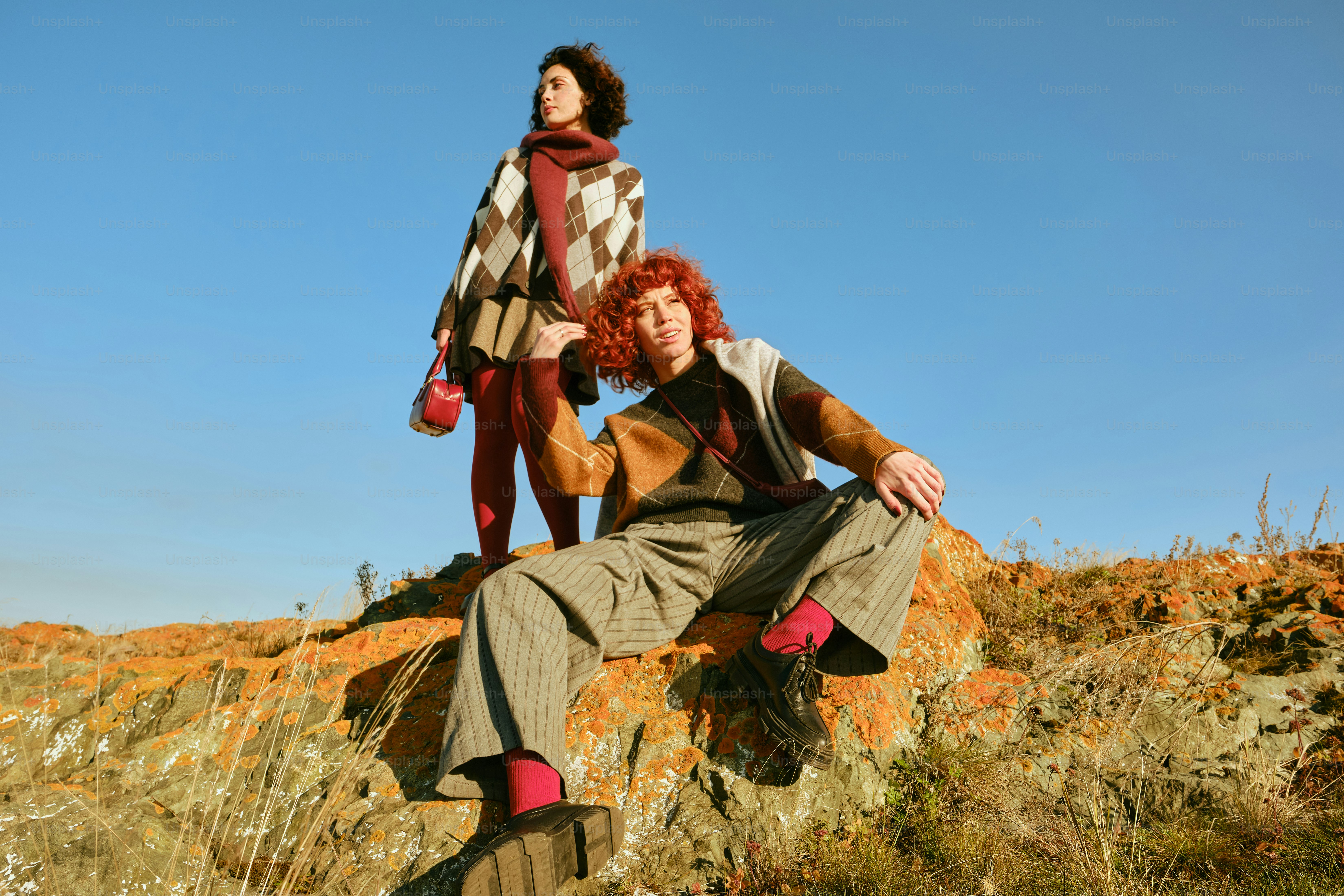 Zwei stilvolle Menschen, die auf einem felsigen Hügel posieren.