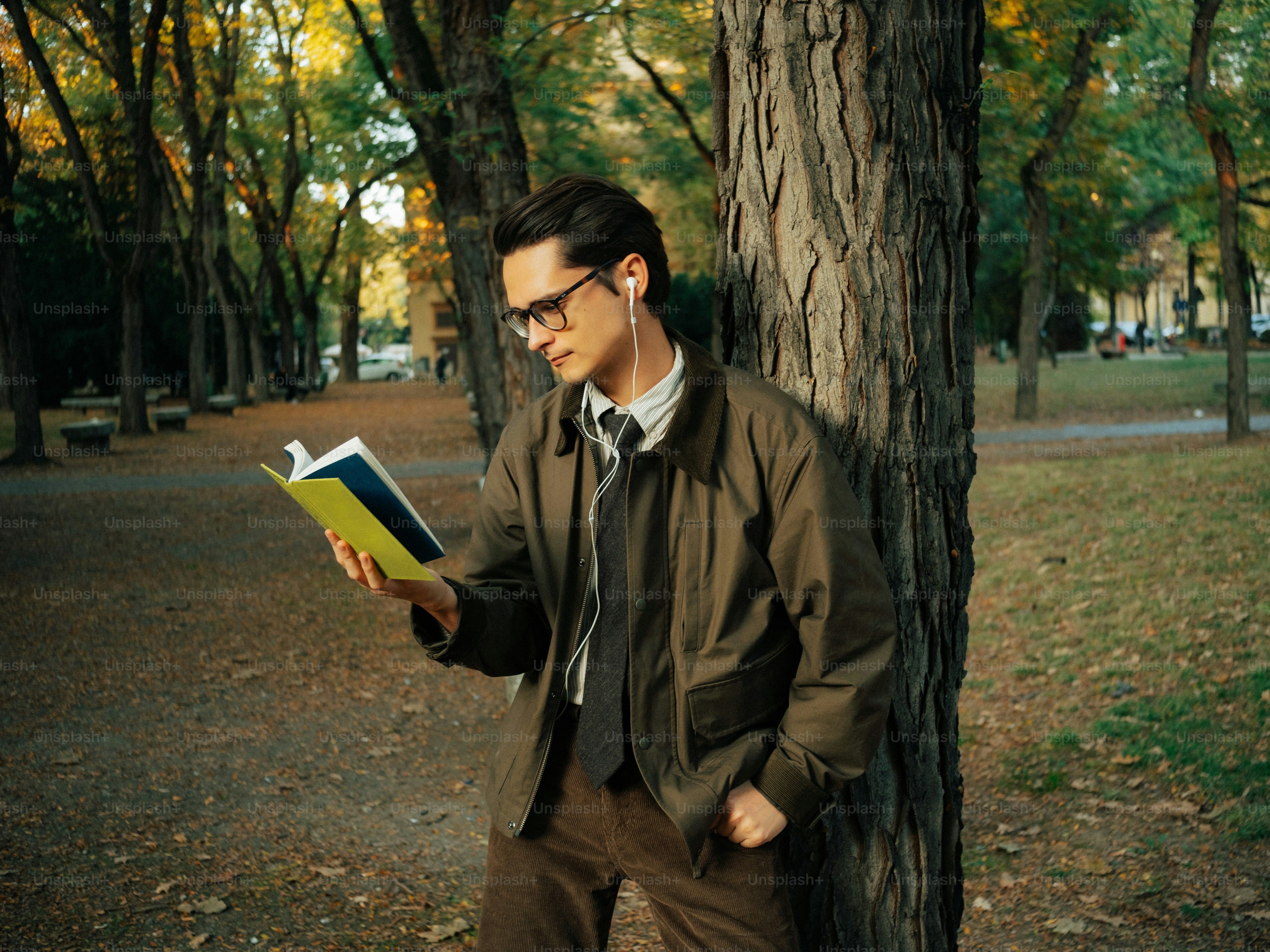 Man with glasses reading book in park