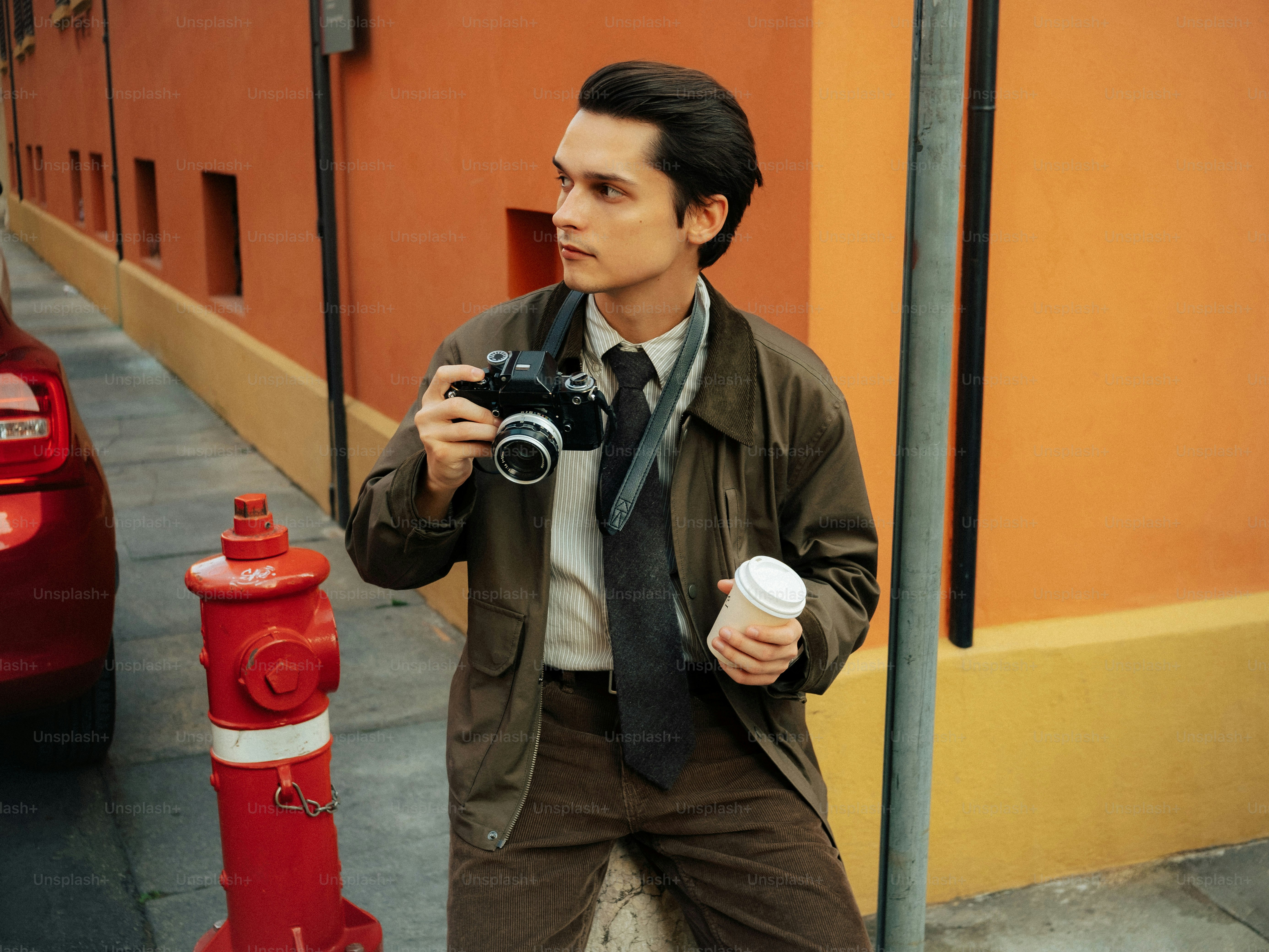 Man holding camera and coffee cup on street