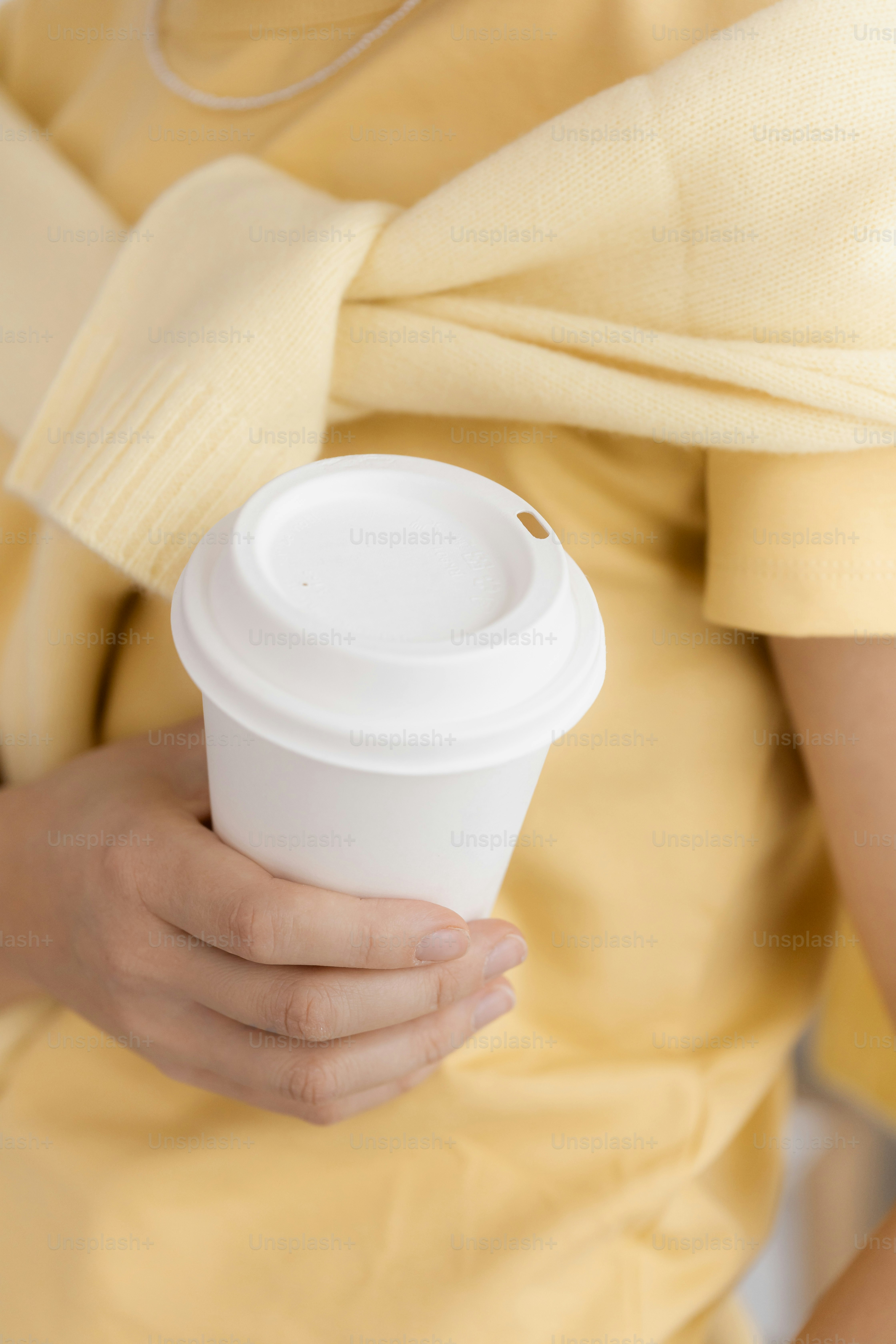 Pessoa segurando uma xícara de café descartável branca.