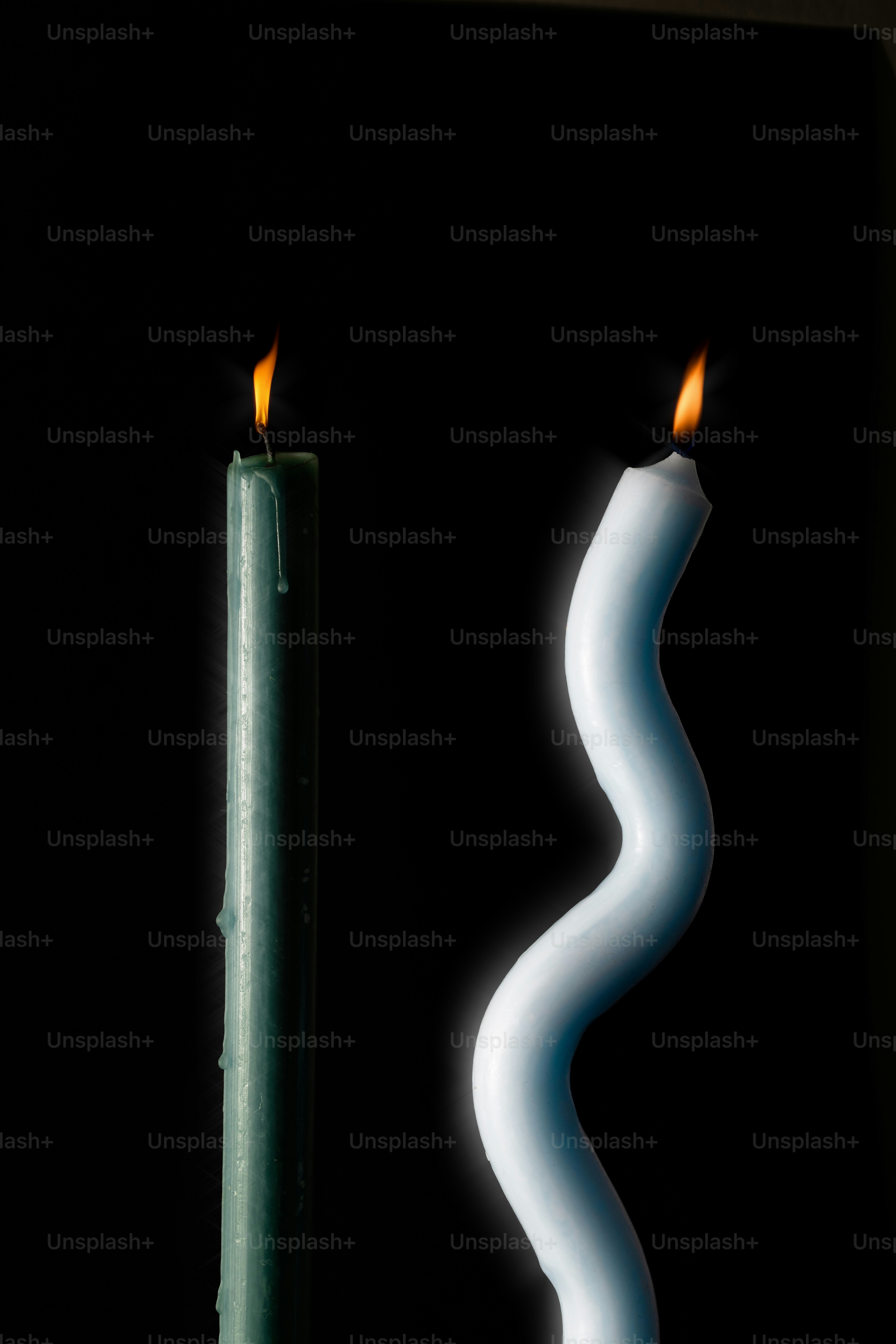 Two lit candles, one straight, one wavy
