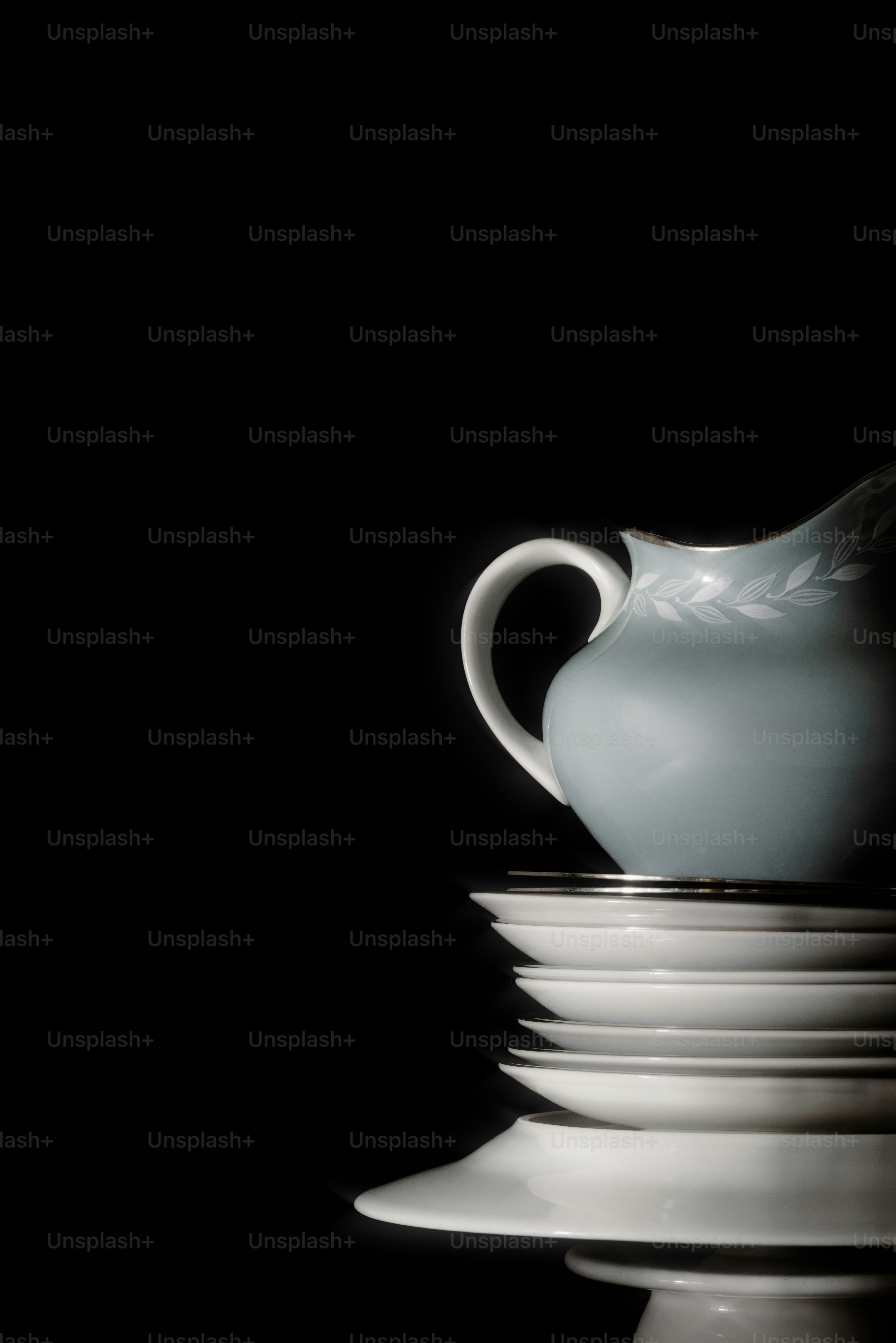 Light blue pitcher atop stack of white plates