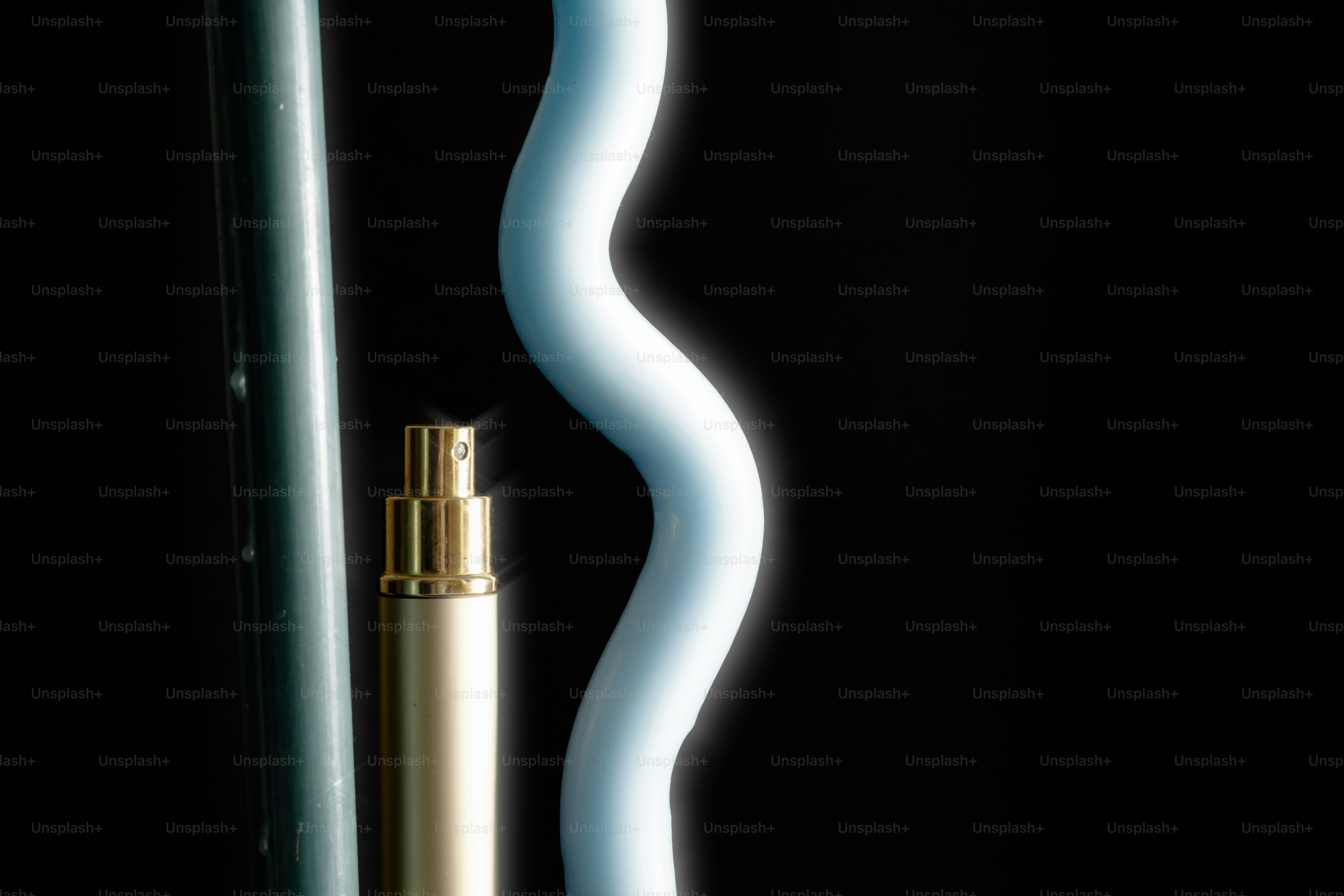 A gold perfume bottle next to a blue wavy object.