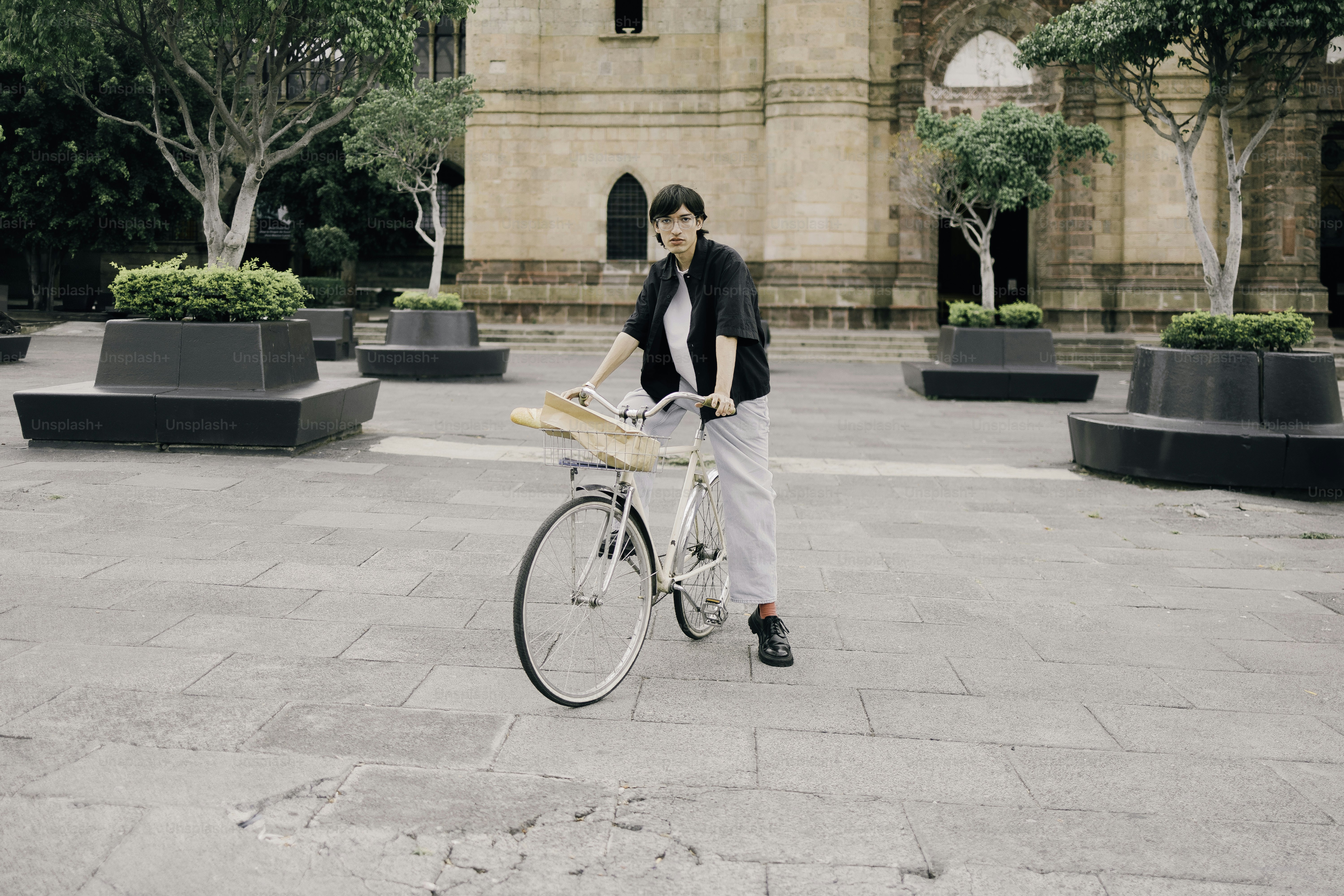 Woman with bicycle and baguette in town square.