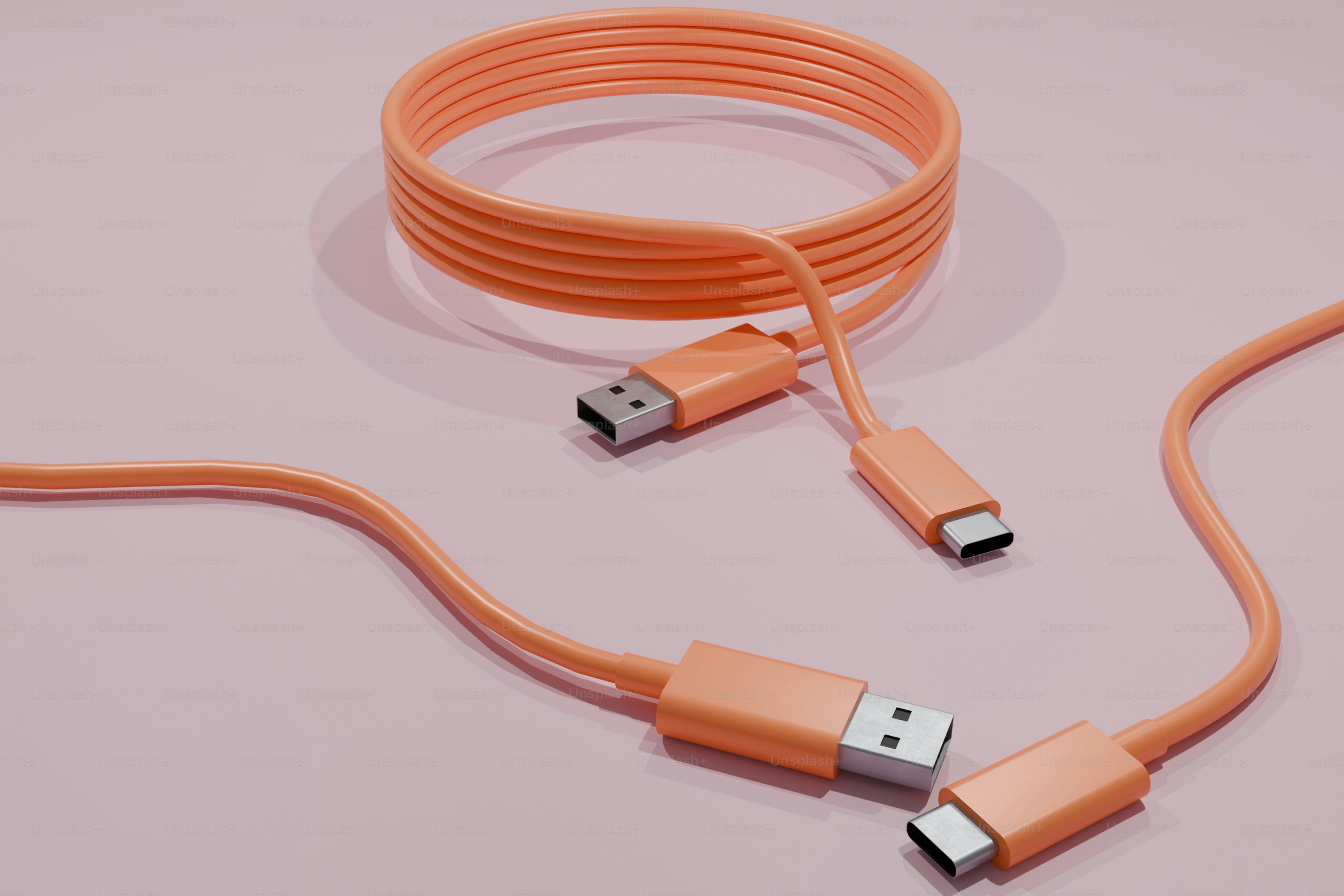 Orangefarbene USB- und USB-C-Kabel auf rosa Hintergrund