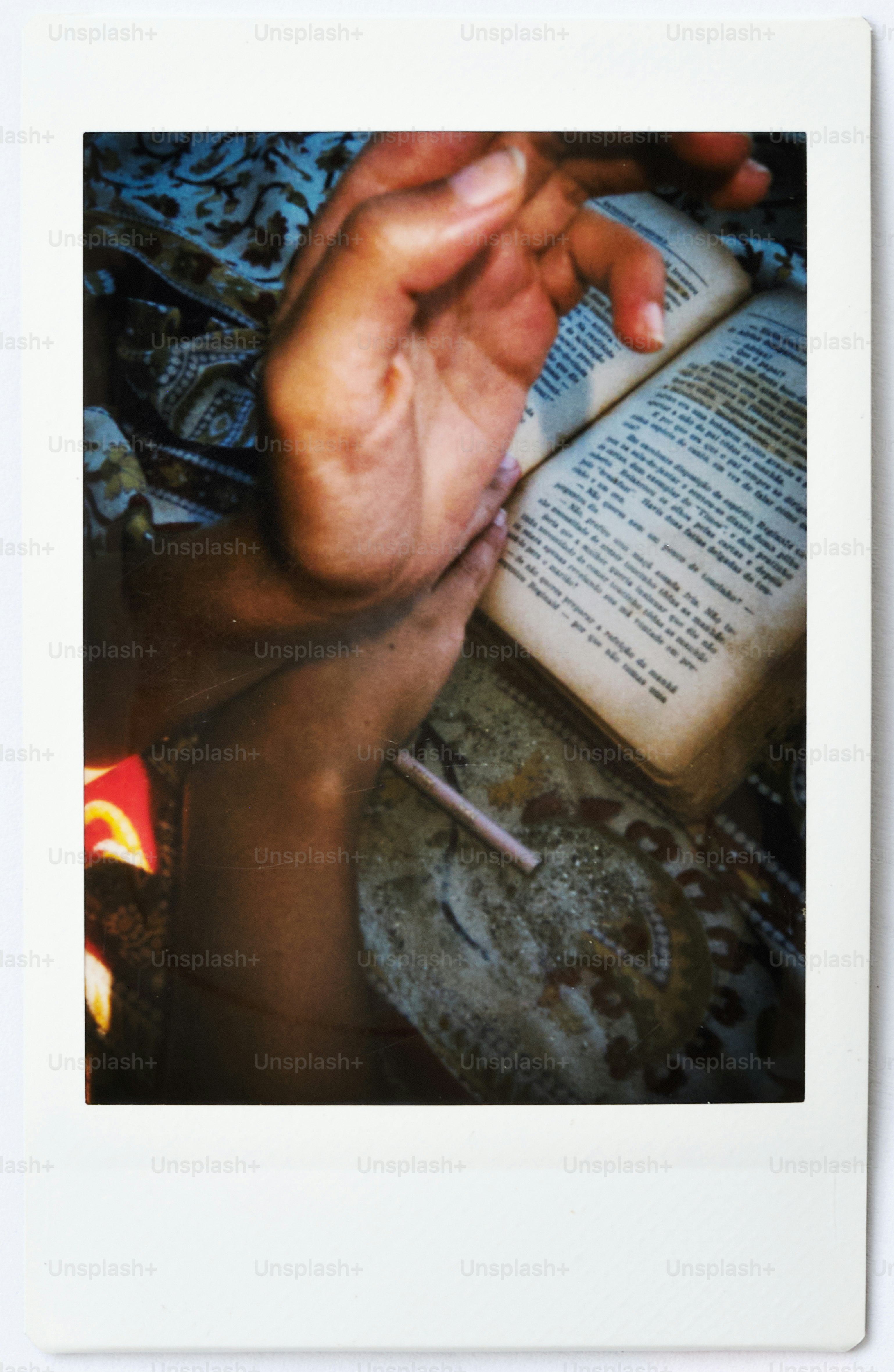 Hand resting on an open book with patterned fabric