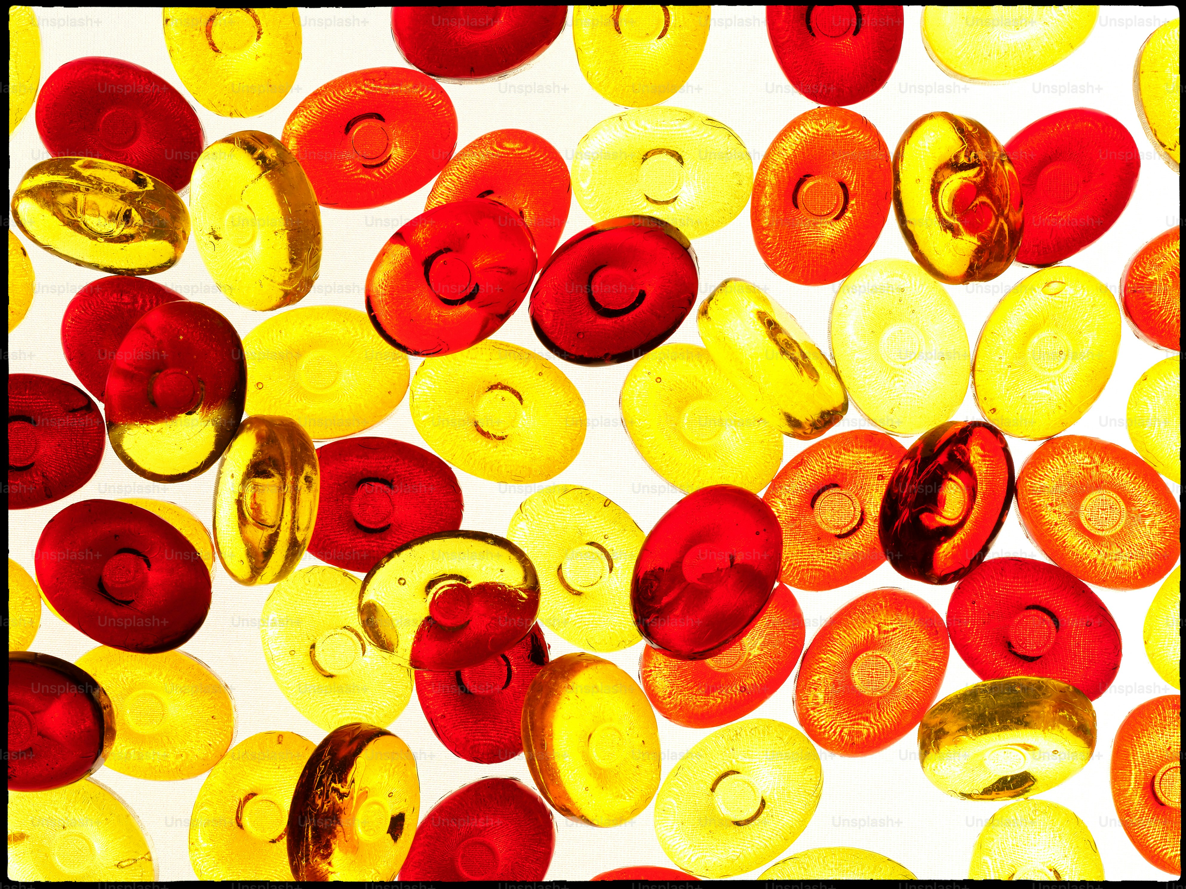 Rote und gelbe ovale Bonbons auf weißem Hintergrund verstreut