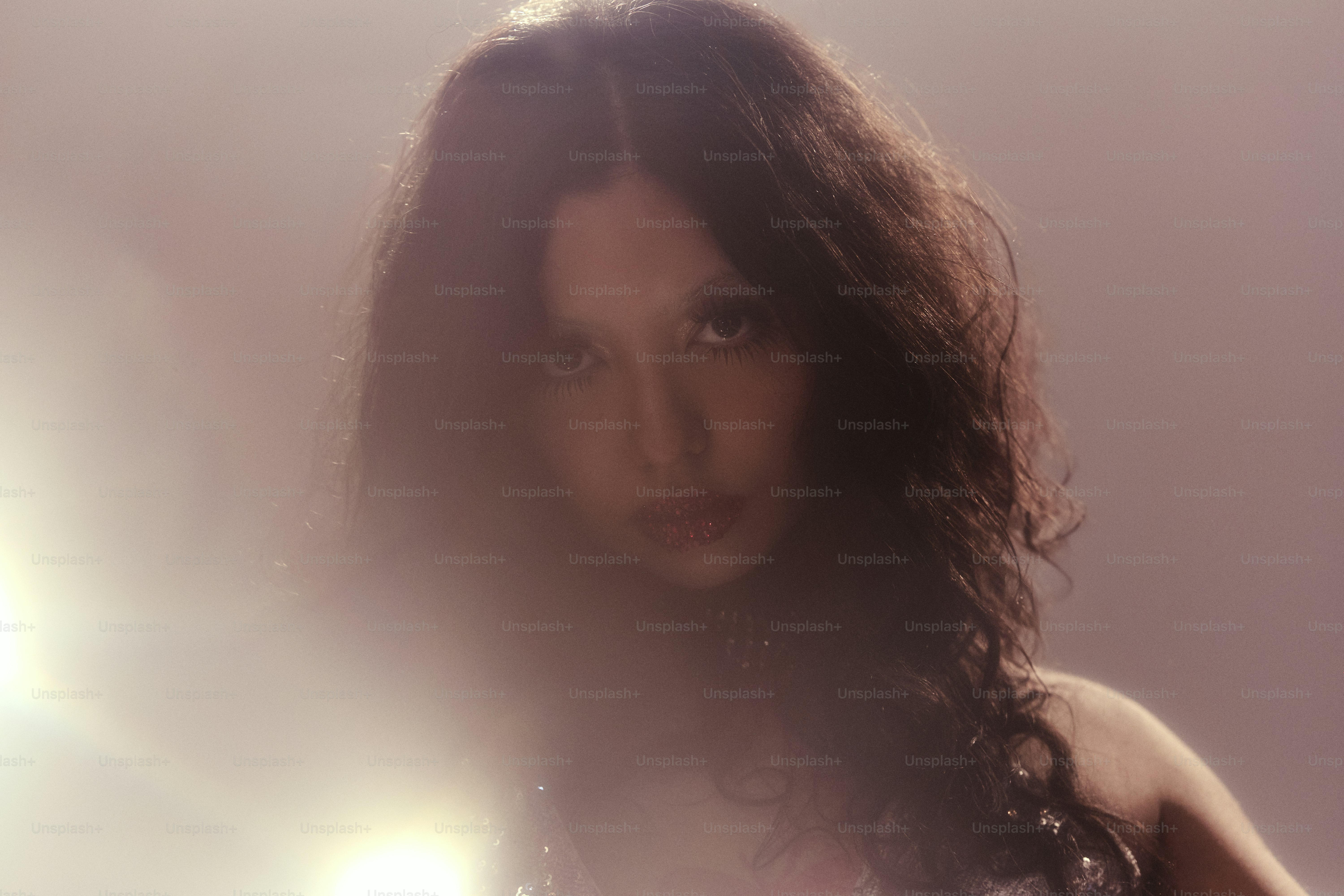 Une femme aux cheveux longs, foncés et ondulés regarde vers l’avant.