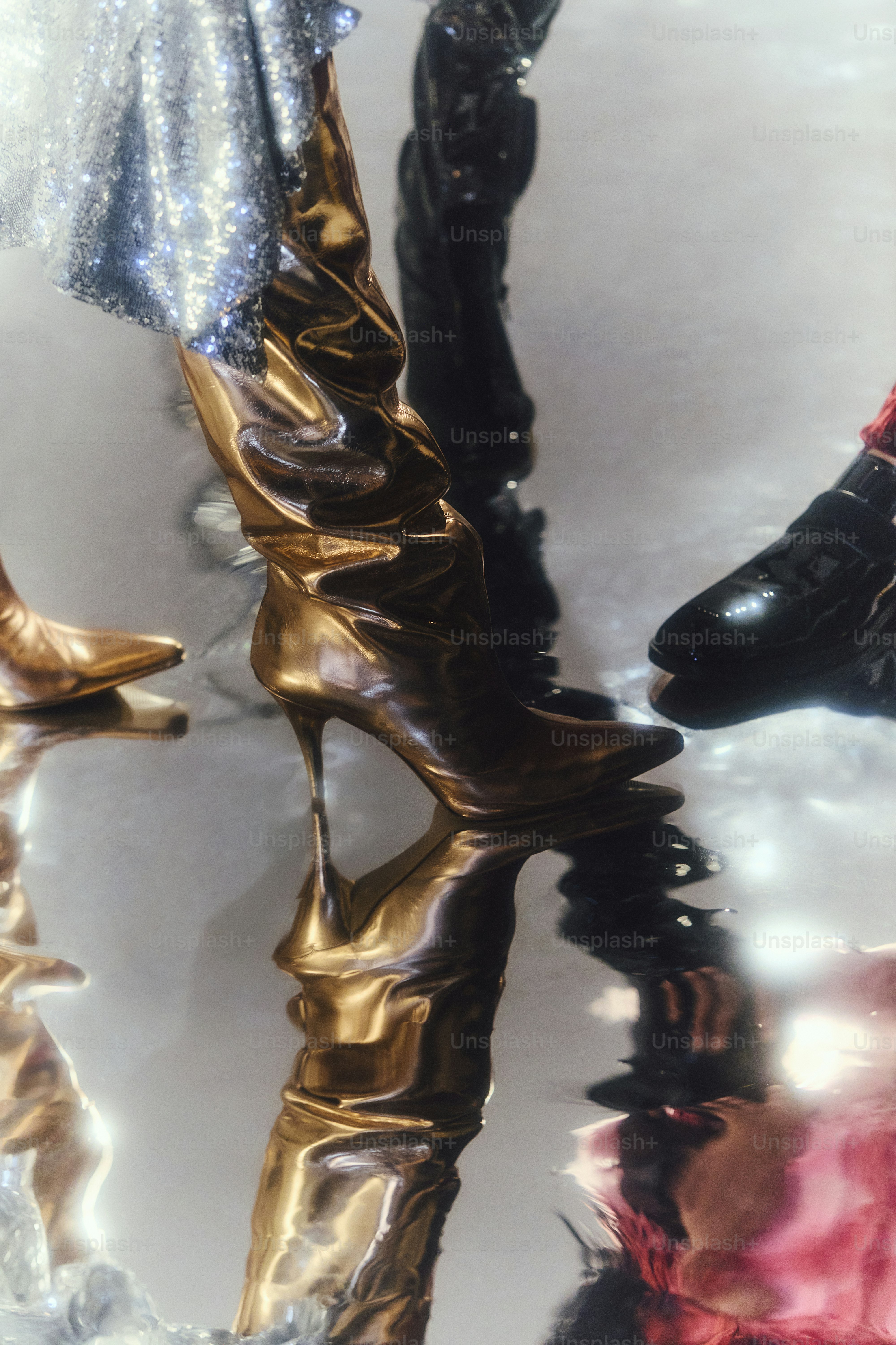 Shiny metallic boots reflected on a mirrored surface.