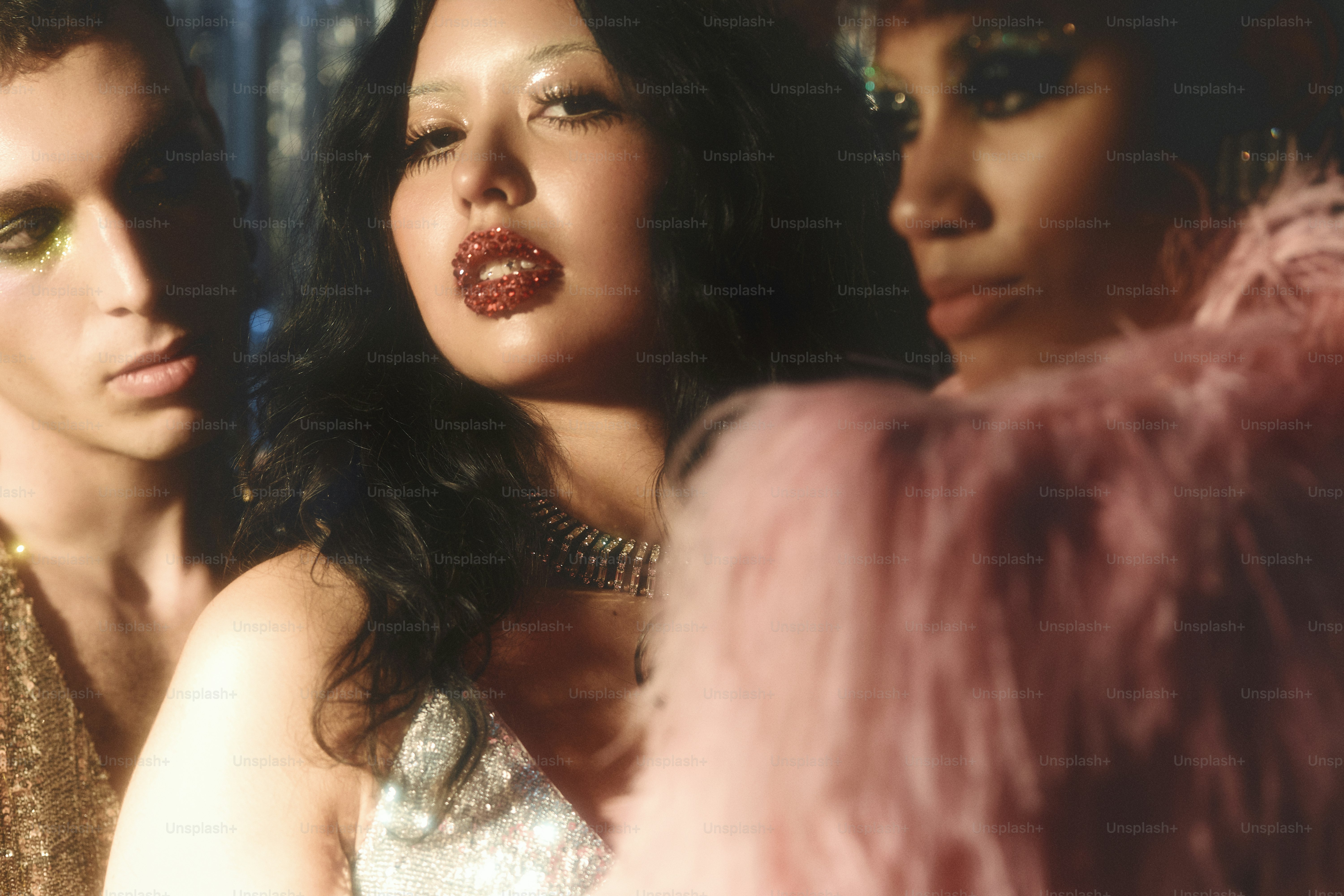 Three people with glitter makeup and glamorous outfits