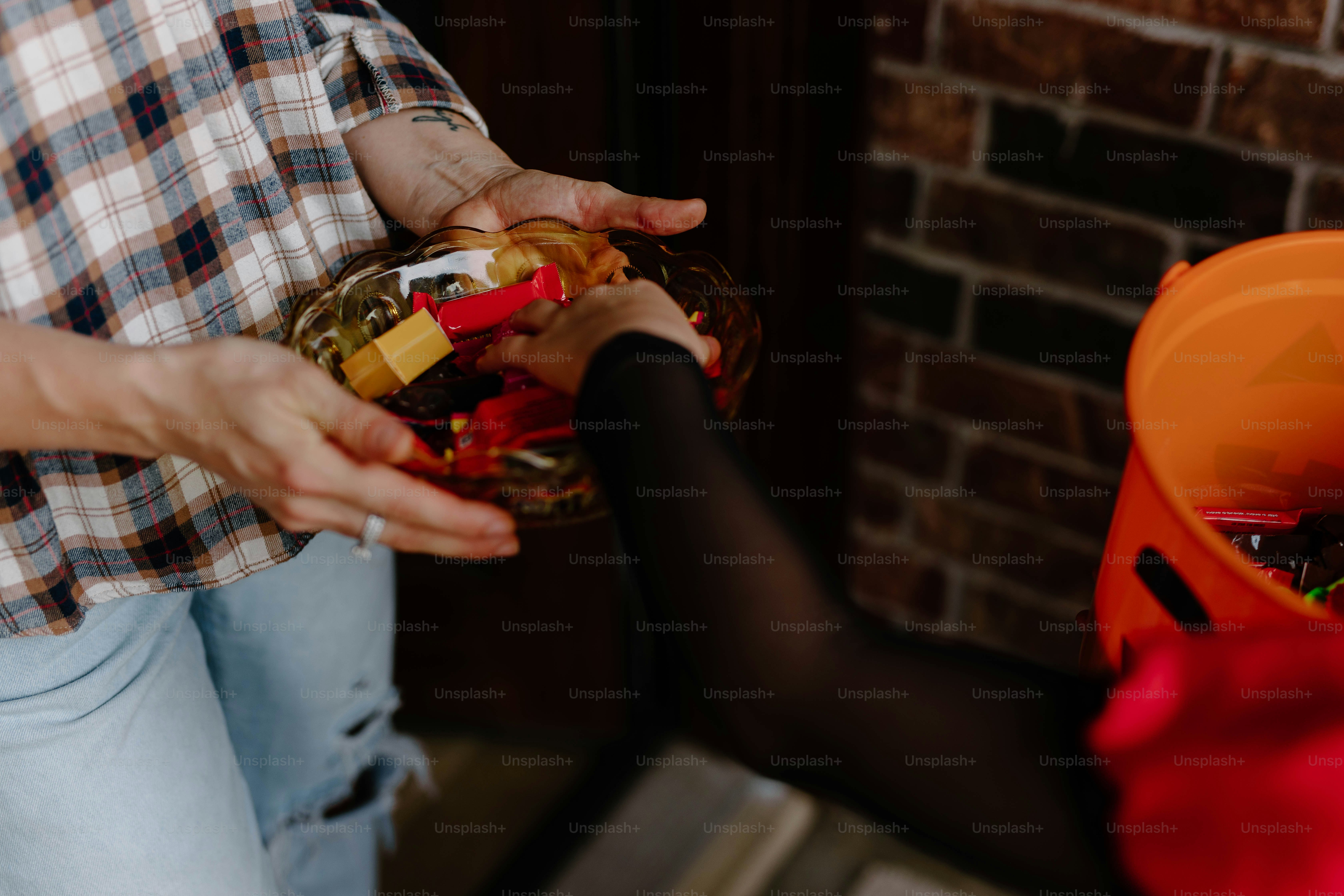Hands offering halloween candy from a bowl
